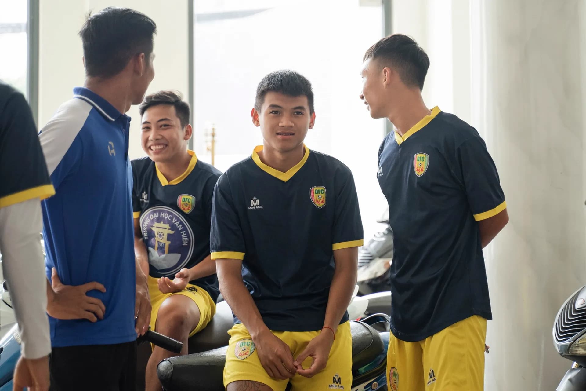 Các cầu thủ trẻ cười thoải mái trong áo thi đấu navy viền vàng trước giờ đo may
