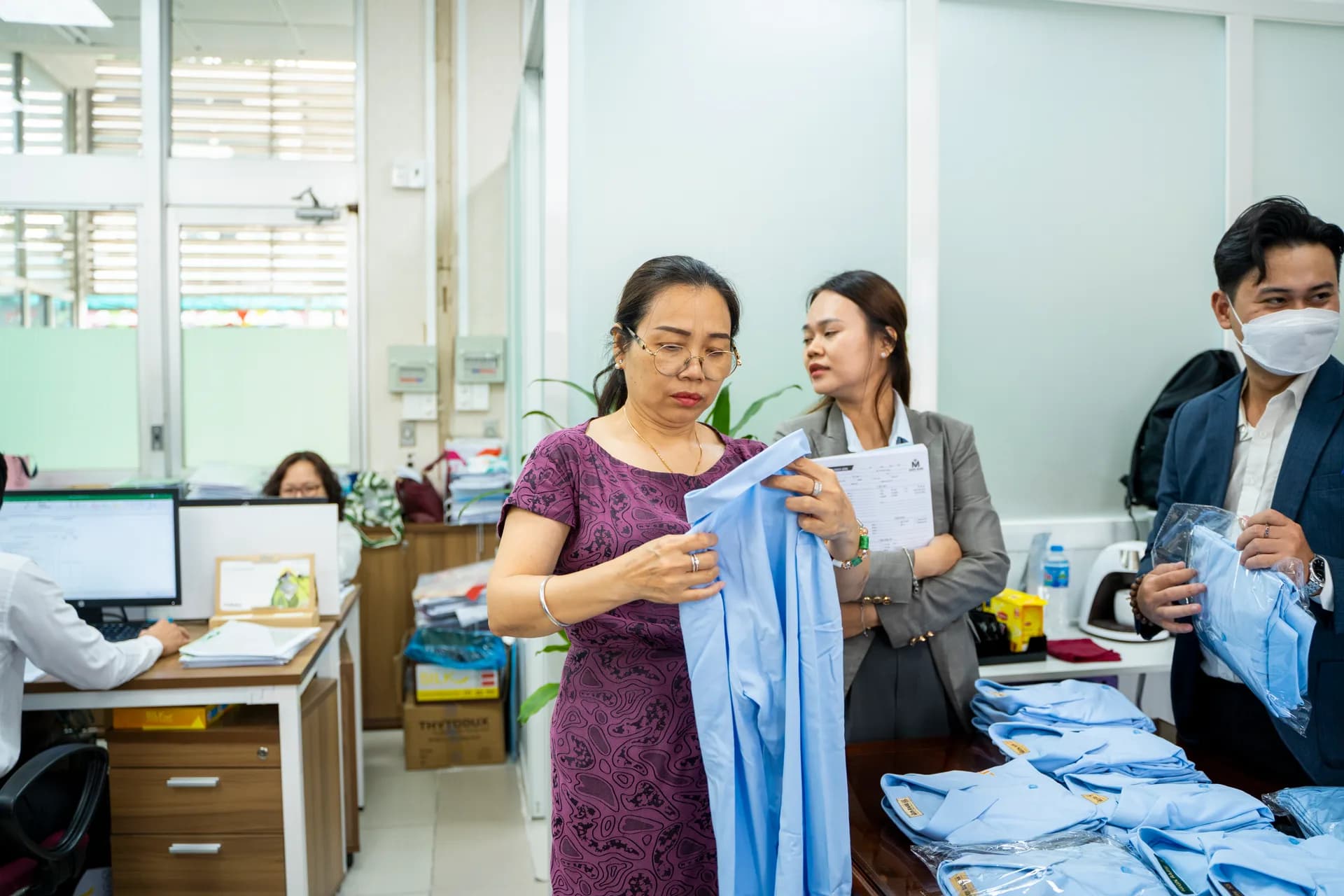 Nhân viên nữ kiểm tra form áo sơ mi đồng phục xanh nhạt
