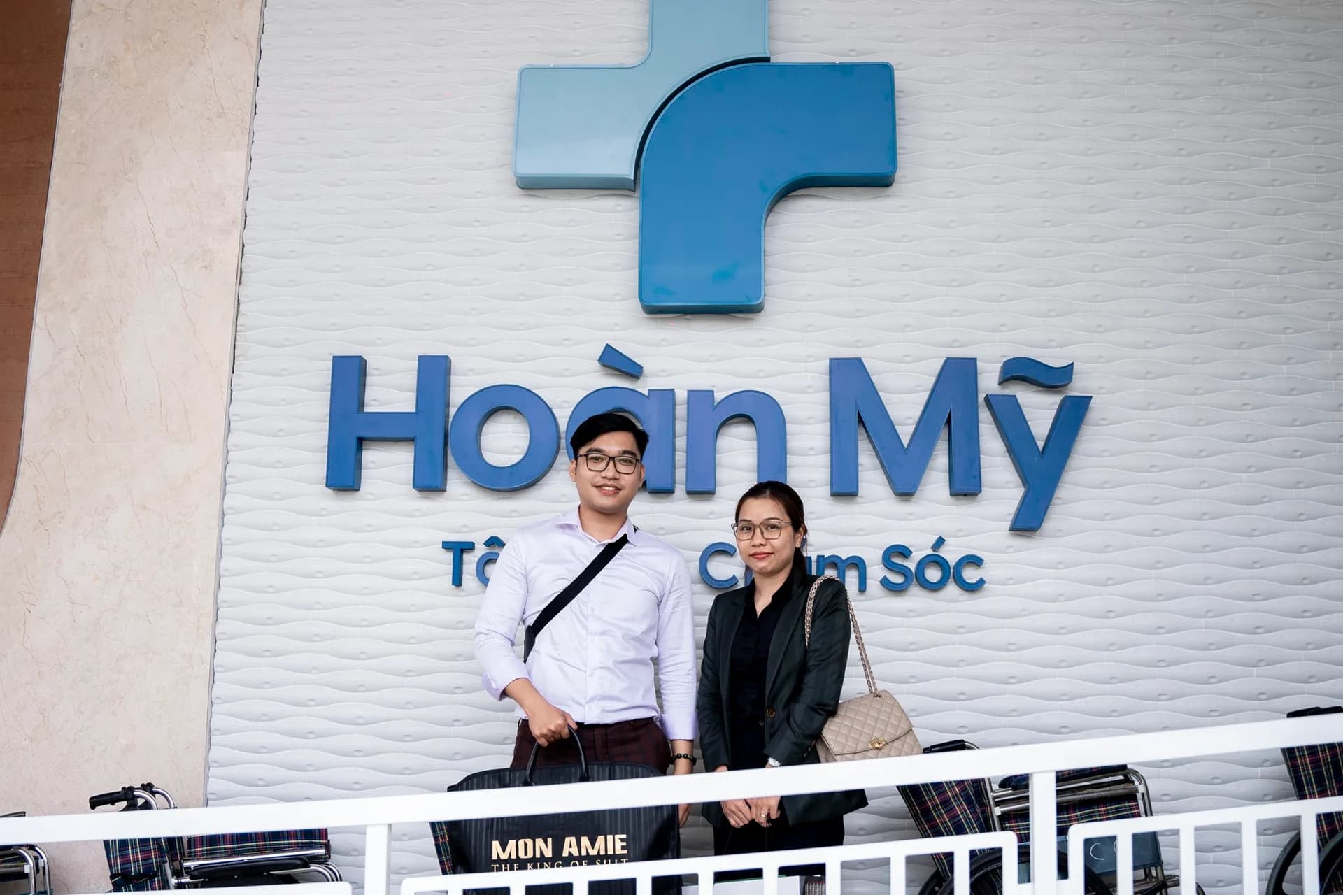 Chụp ảnh trước bảng hiệu Bệnh viện Hoàn Mỹ cùng túi Mon Amie