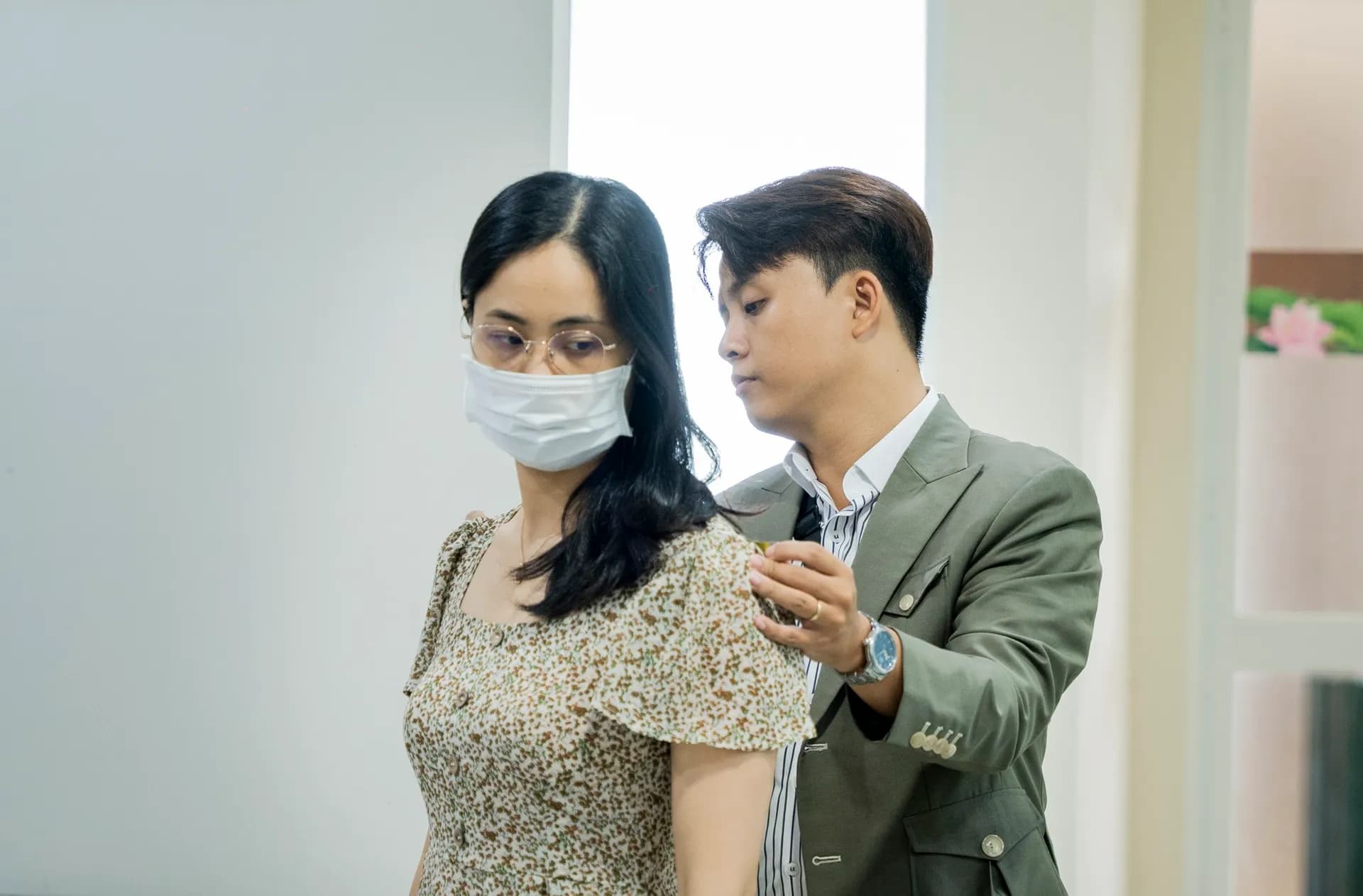 Đo vai cho khách nữ áo hoa nhí, thợ mặc blazer xanh rêu