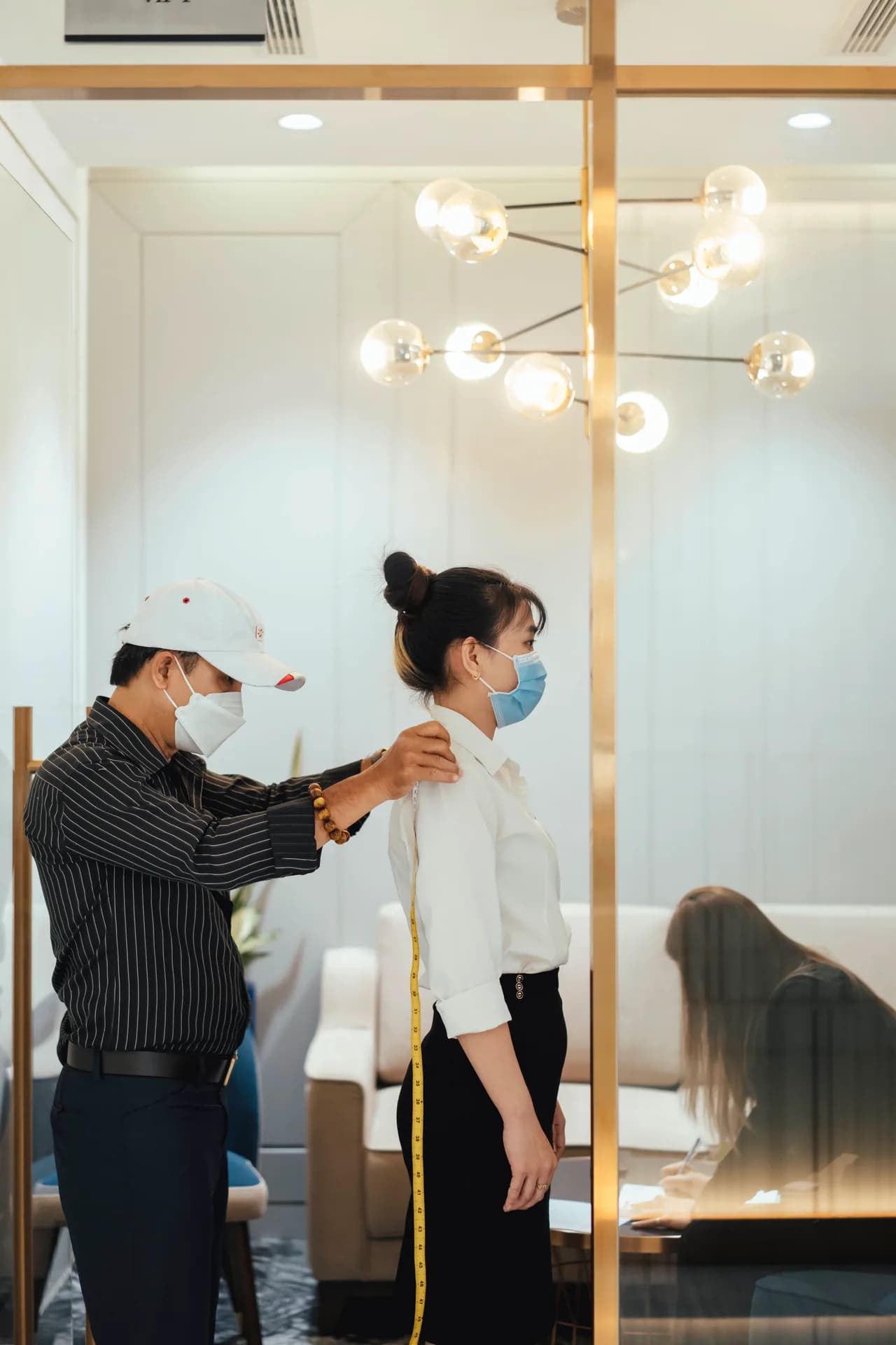 Thợ may đo chiều dài lưng áo cho nhân viên nữ