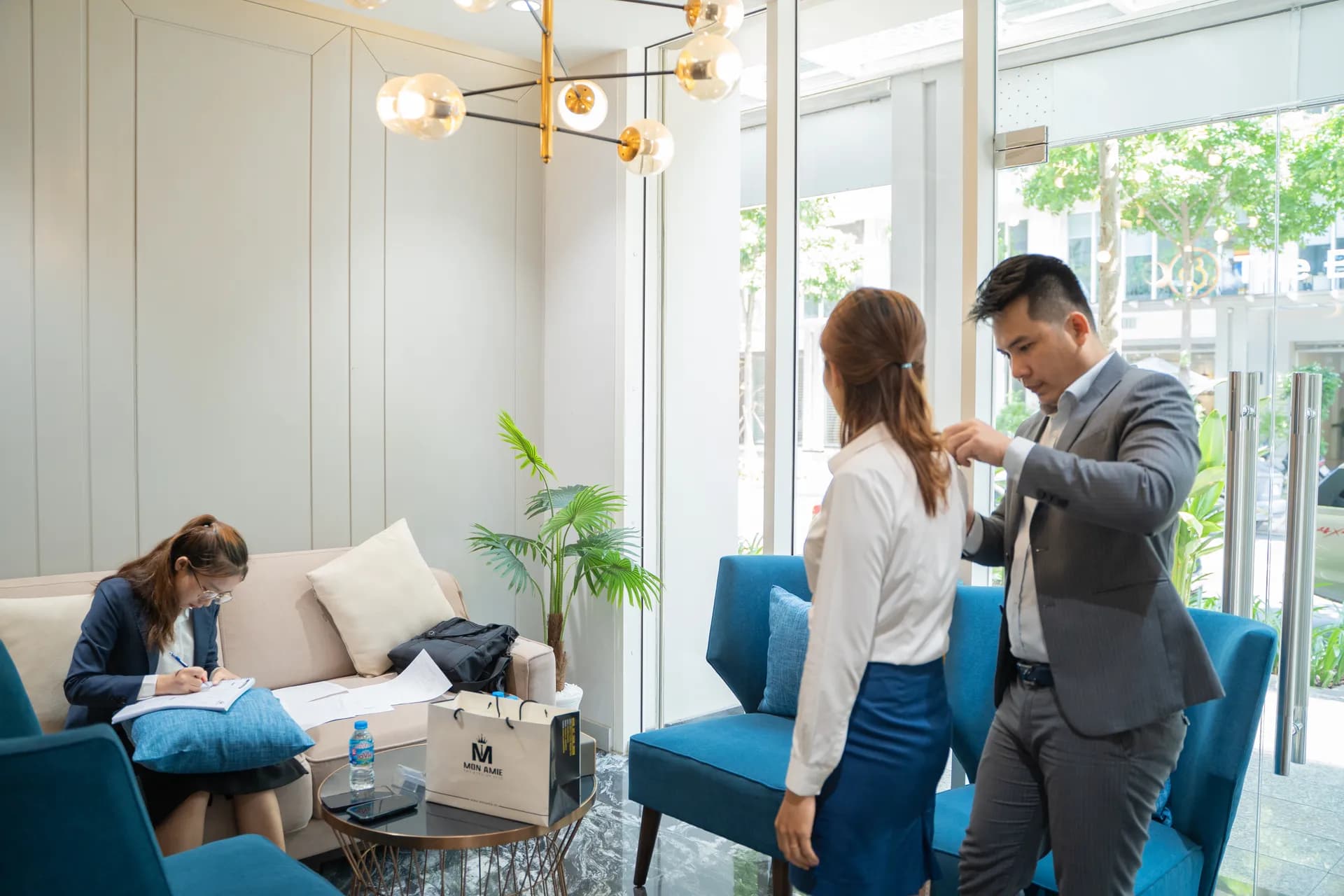 Đo may tại phòng chờ ghế xanh ngọc, ánh nắng qua cửa kính, túi Mon Amie trên bàn