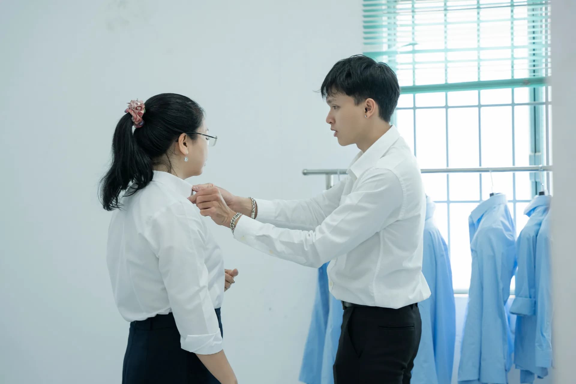 Chỉnh cổ áo sơ mi trắng cho nhân viên nữ trong buổi thử đồng phục