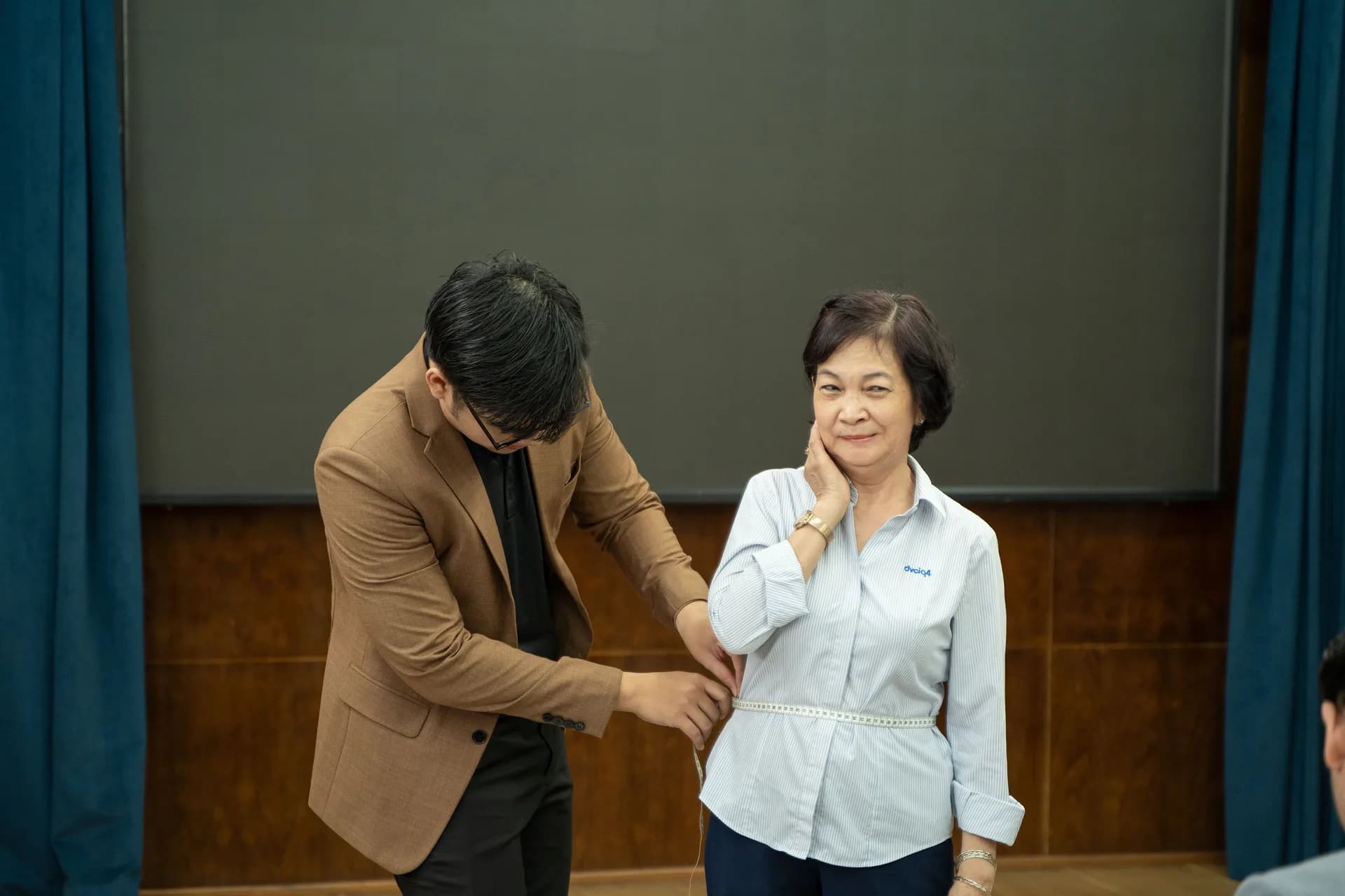 Đo vòng eo cho nhân viên nữ lớn tuổi, thao tác nhẹ nhàng và tỉ mỉ