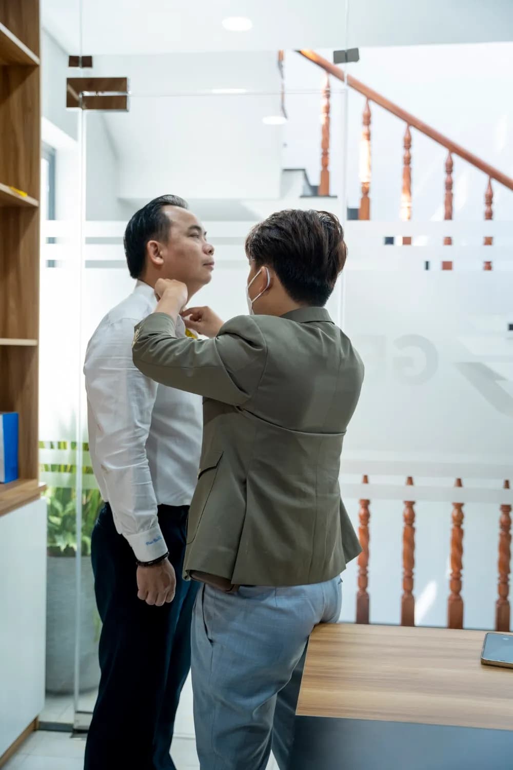 Đo vòng cổ cho khách áo sơ mi trắng bên cầu thang kính, ánh sáng tự nhiên