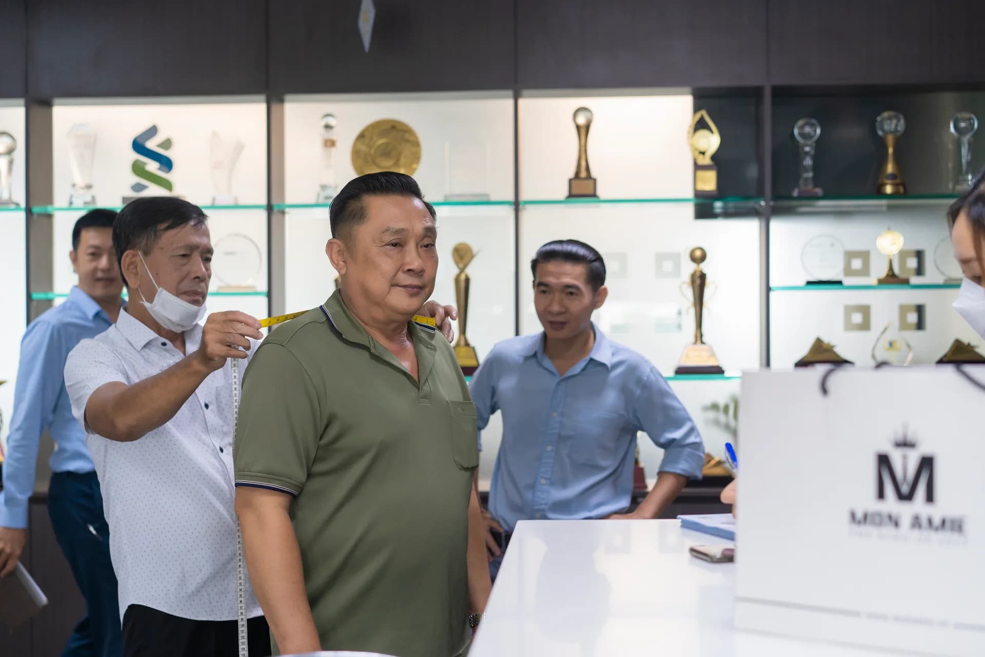 Đo vai cho cán bộ áo polo xanh rêu tại tủ cúp