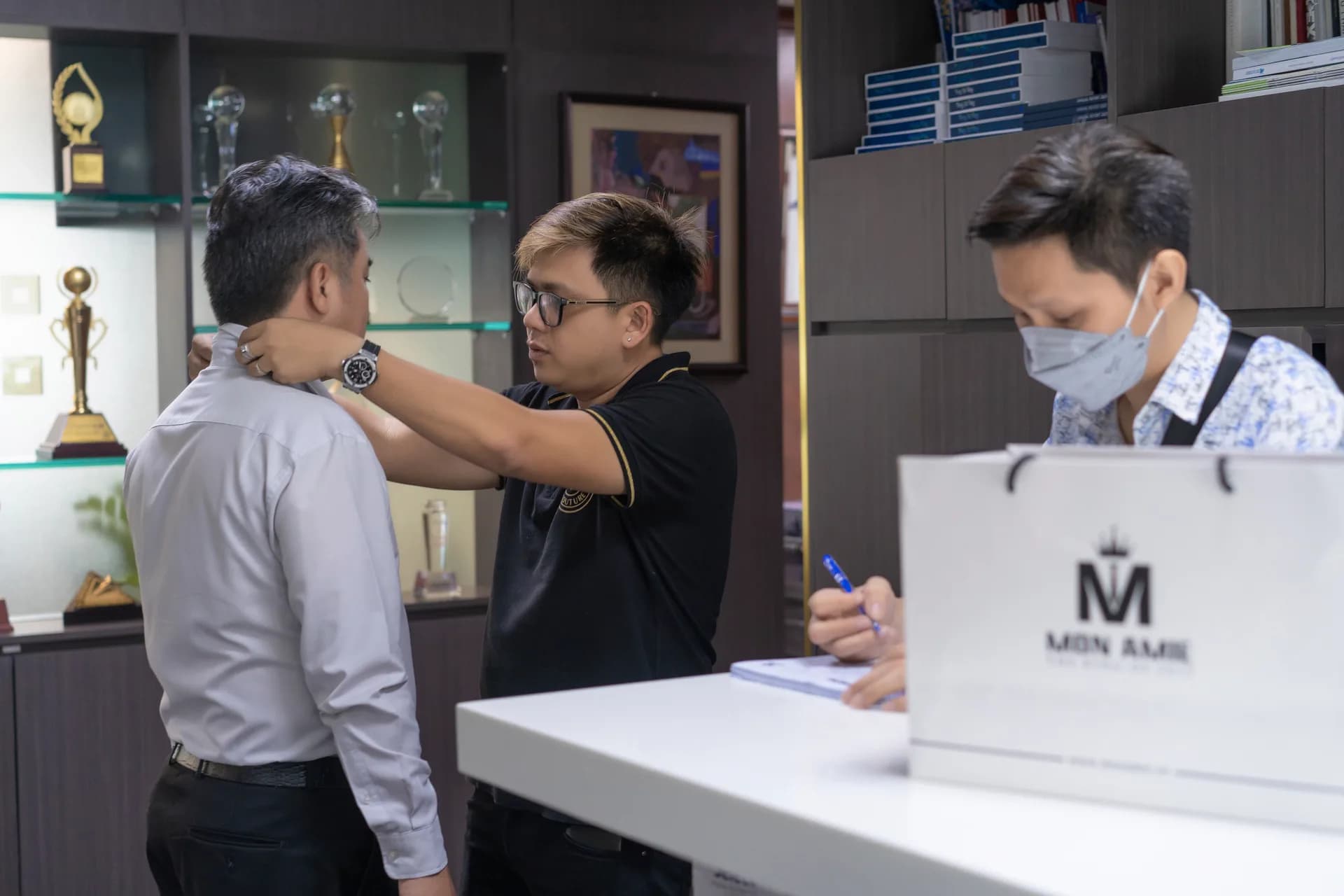 Đo vòng cổ cho cán bộ, người ghi số đo bên cạnh