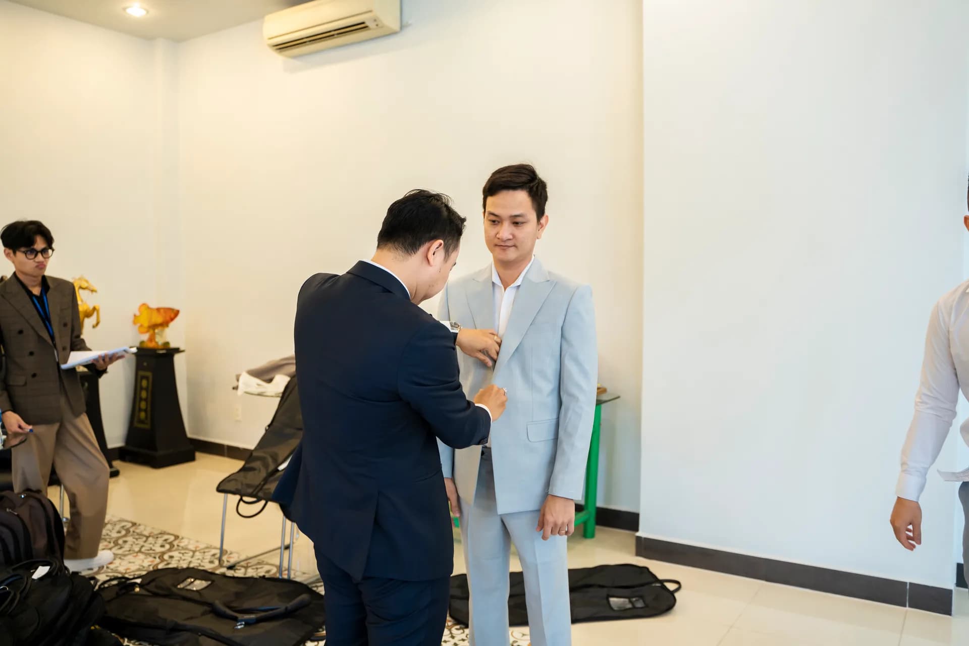 Chuyên viên ghim chỉnh áo vest xanh nhạt trên người nhân viên