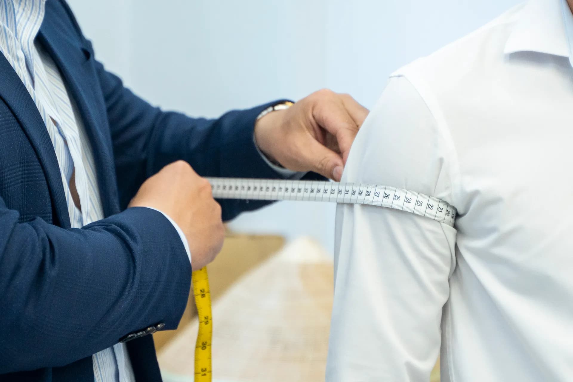 Cận cảnh thước dây đo vòng bắp tay áo sơ mi trắng, thợ may vest navy