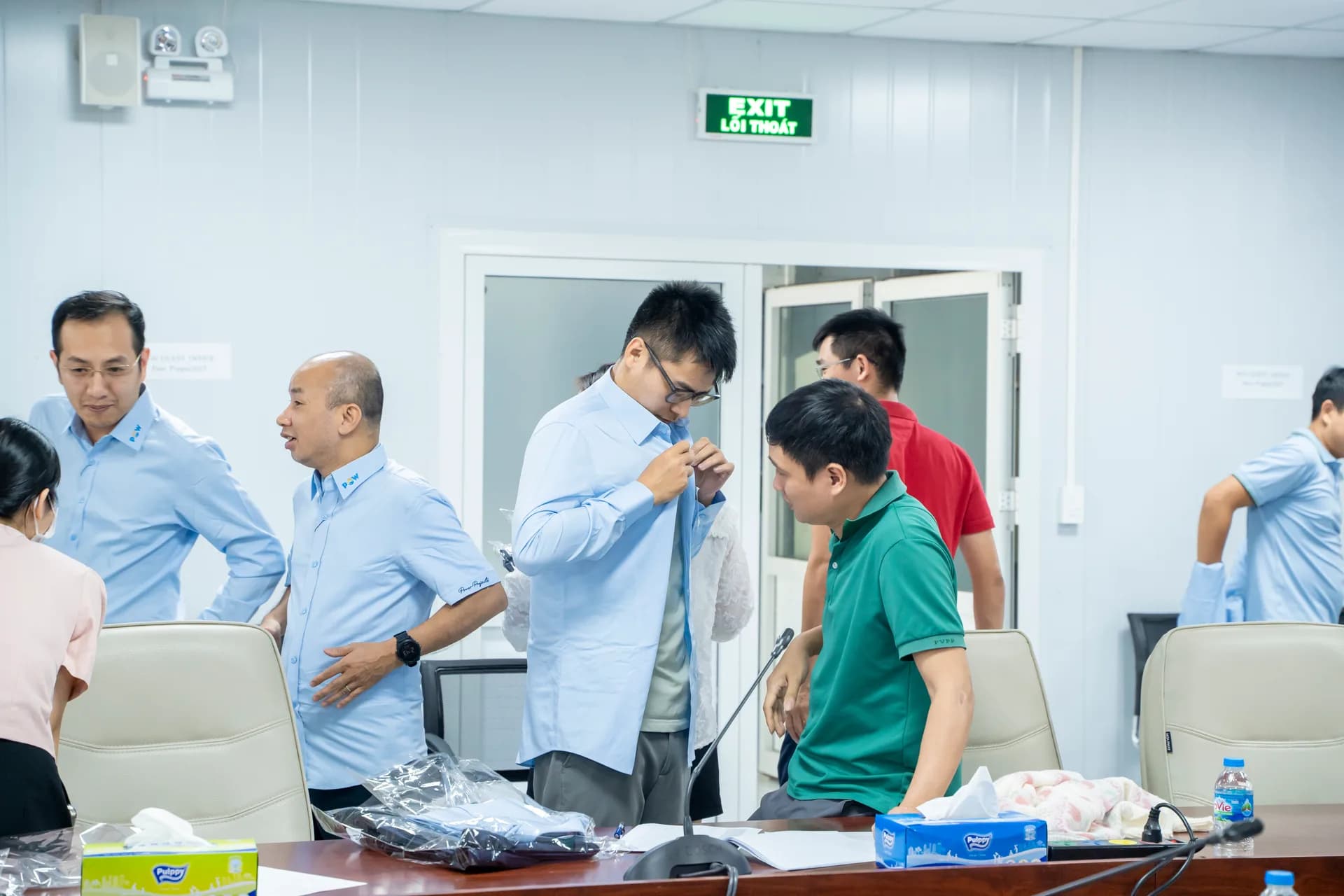 Nhân viên mặc thử sơ mi đồng phục xanh nhạt ngay tại phòng họp