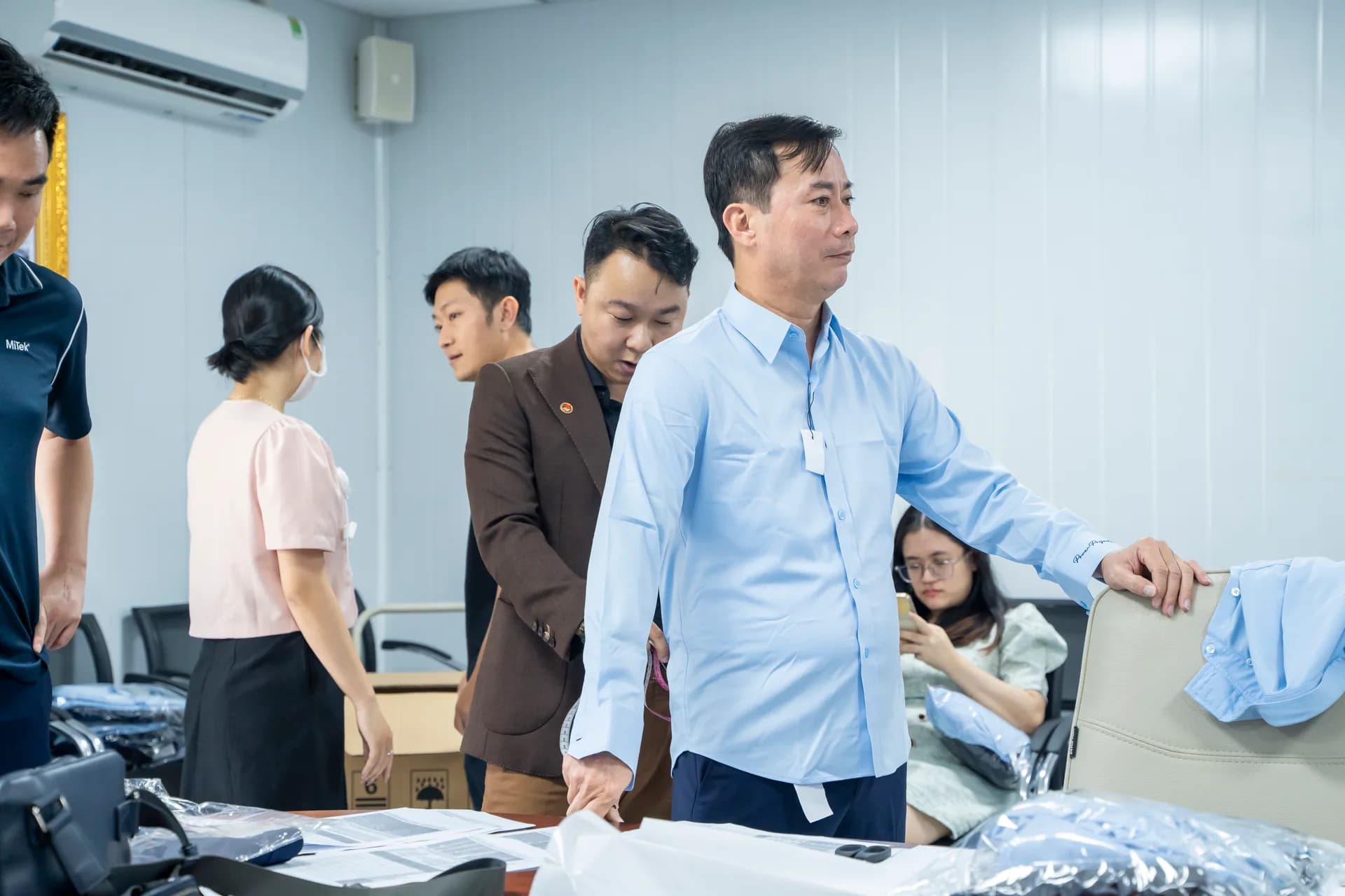 Nhân viên công ty chọn size và nhận đồng phục sơ mi xanh nhạt