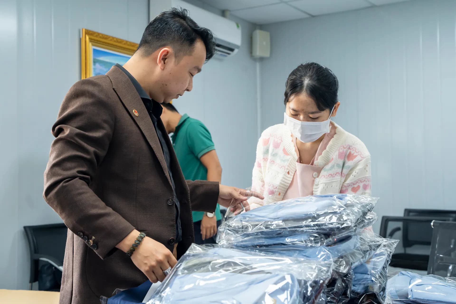 Giao đồng phục: kiểm từng gói áo trong túi nilon xếp chồng cùng nhân viên khách hàng