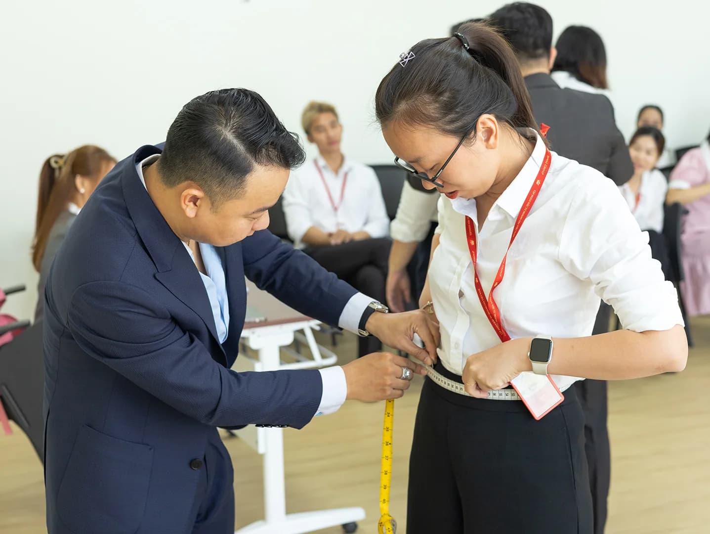 Đo vòng eo cho nhân viên nữ đeo thẻ, đồng nghiệp chờ đến lượt phía sau