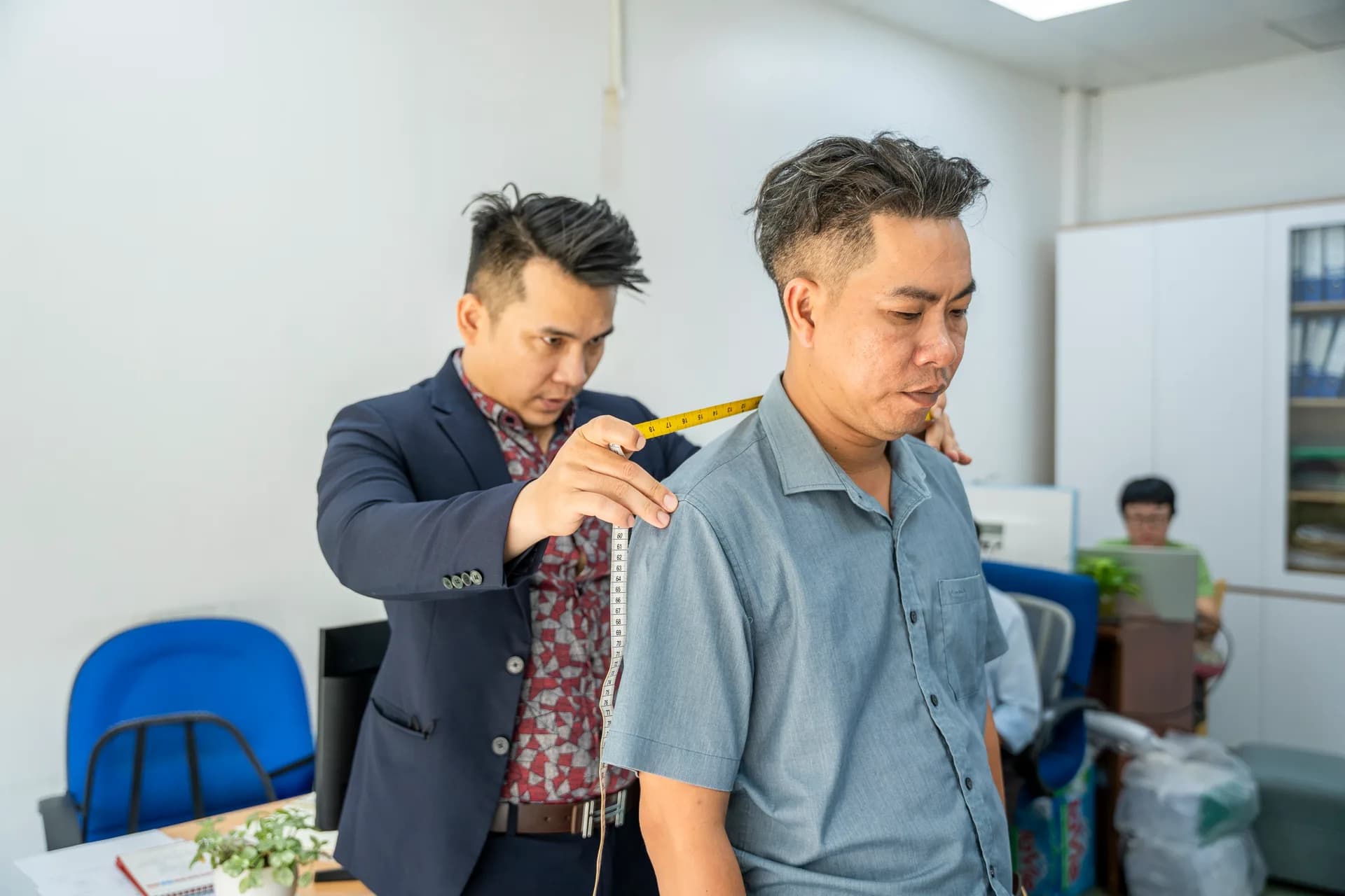 Đo vai cho nhân viên nam tại phòng làm việc