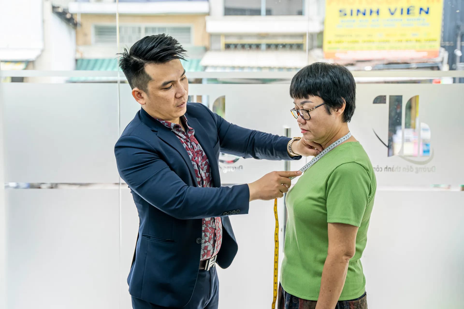 Đo vòng cổ cho khách nữ áo xanh lá trong buổi đo đồng phục