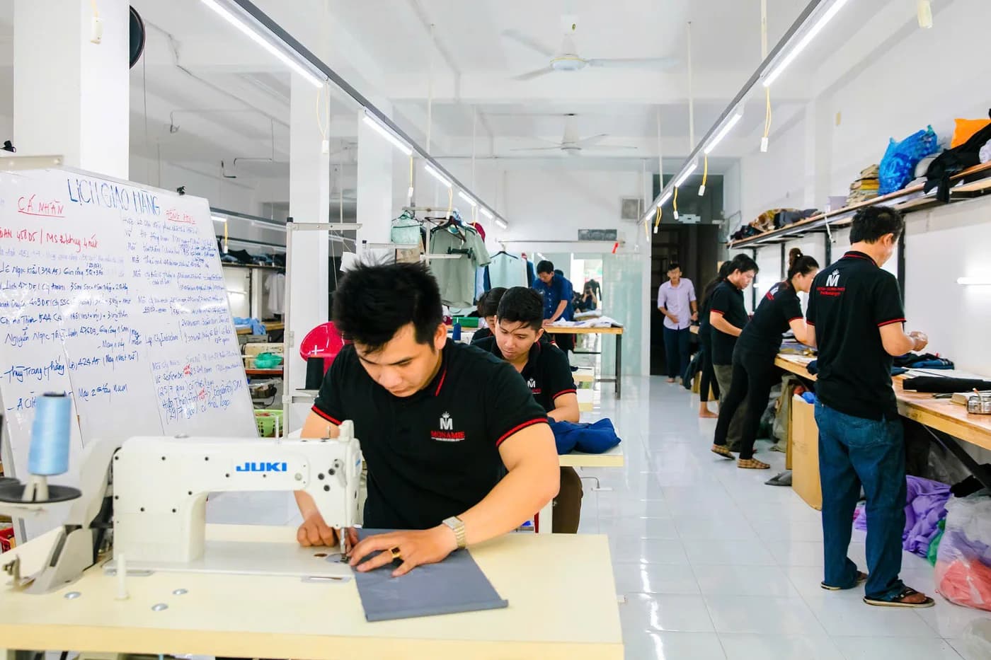 Đội thợ đồng phục polo đen viền đỏ bên máy Juki