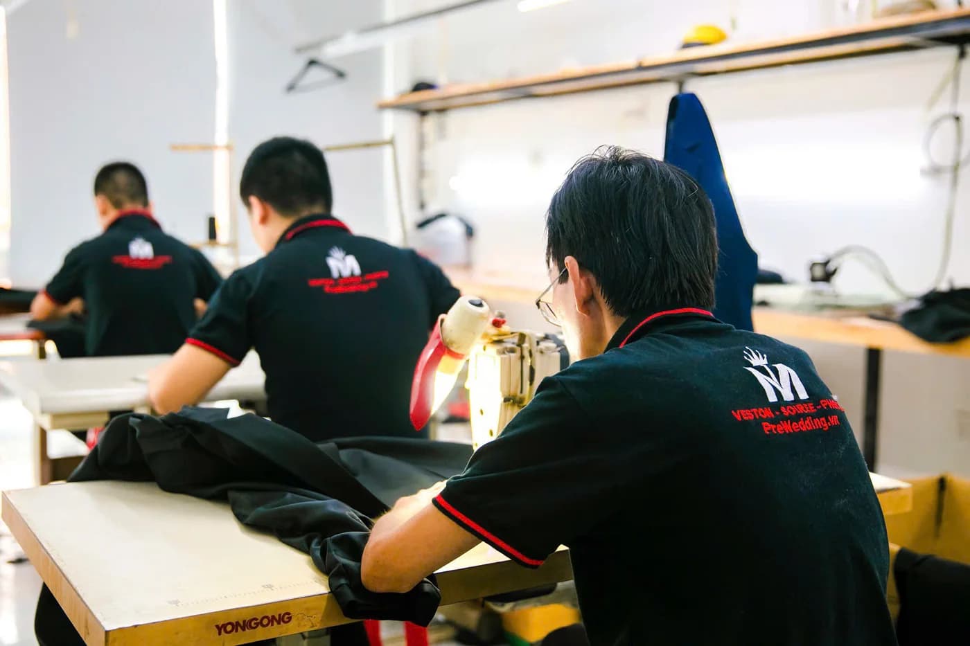 Ba thợ áo polo đồng phục đen in logo Mon Amie ngồi may