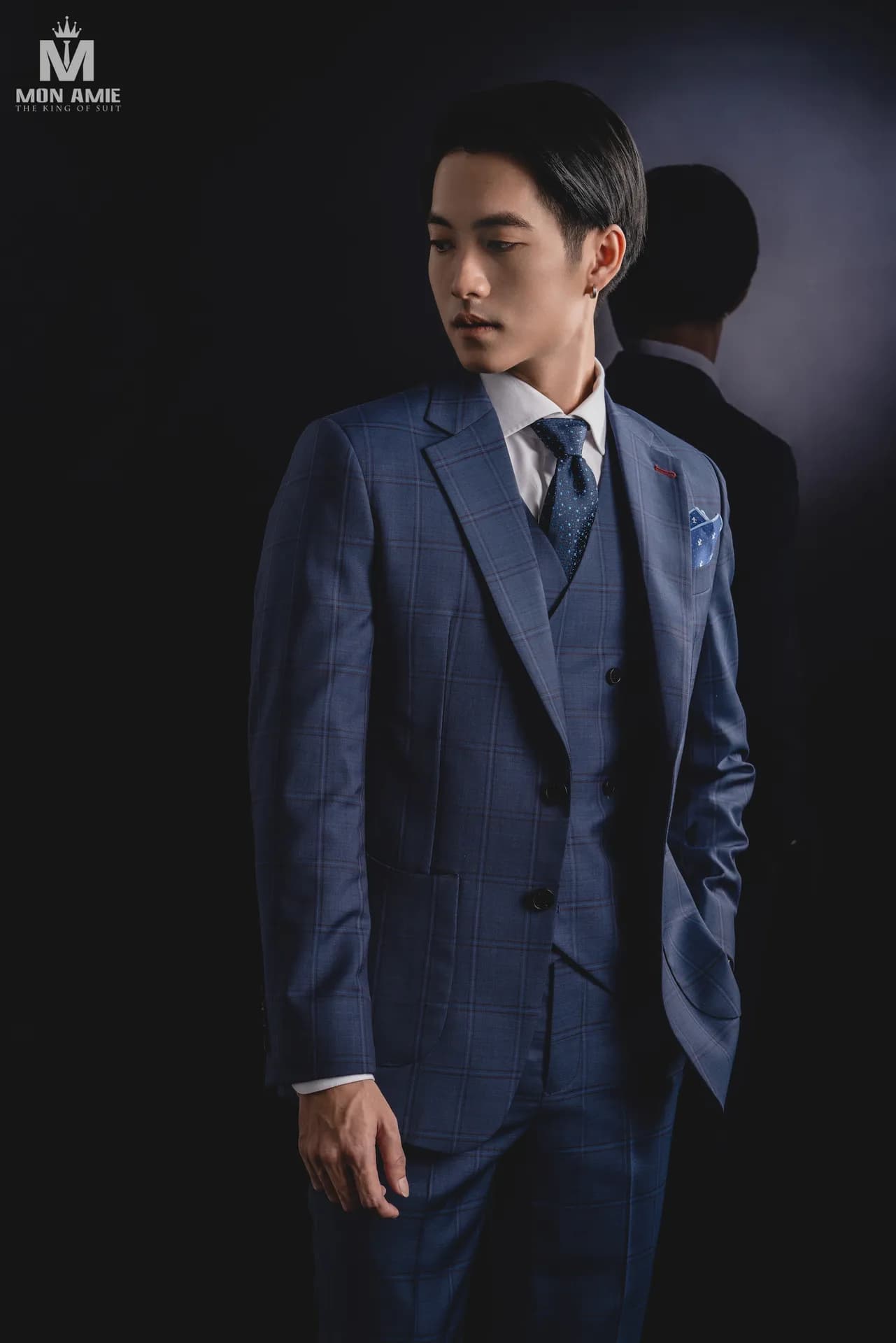 Suit xanh navy caro ba mảnh, cà vạt chấm bi, khăn cài túi xanh, nền studio tối
