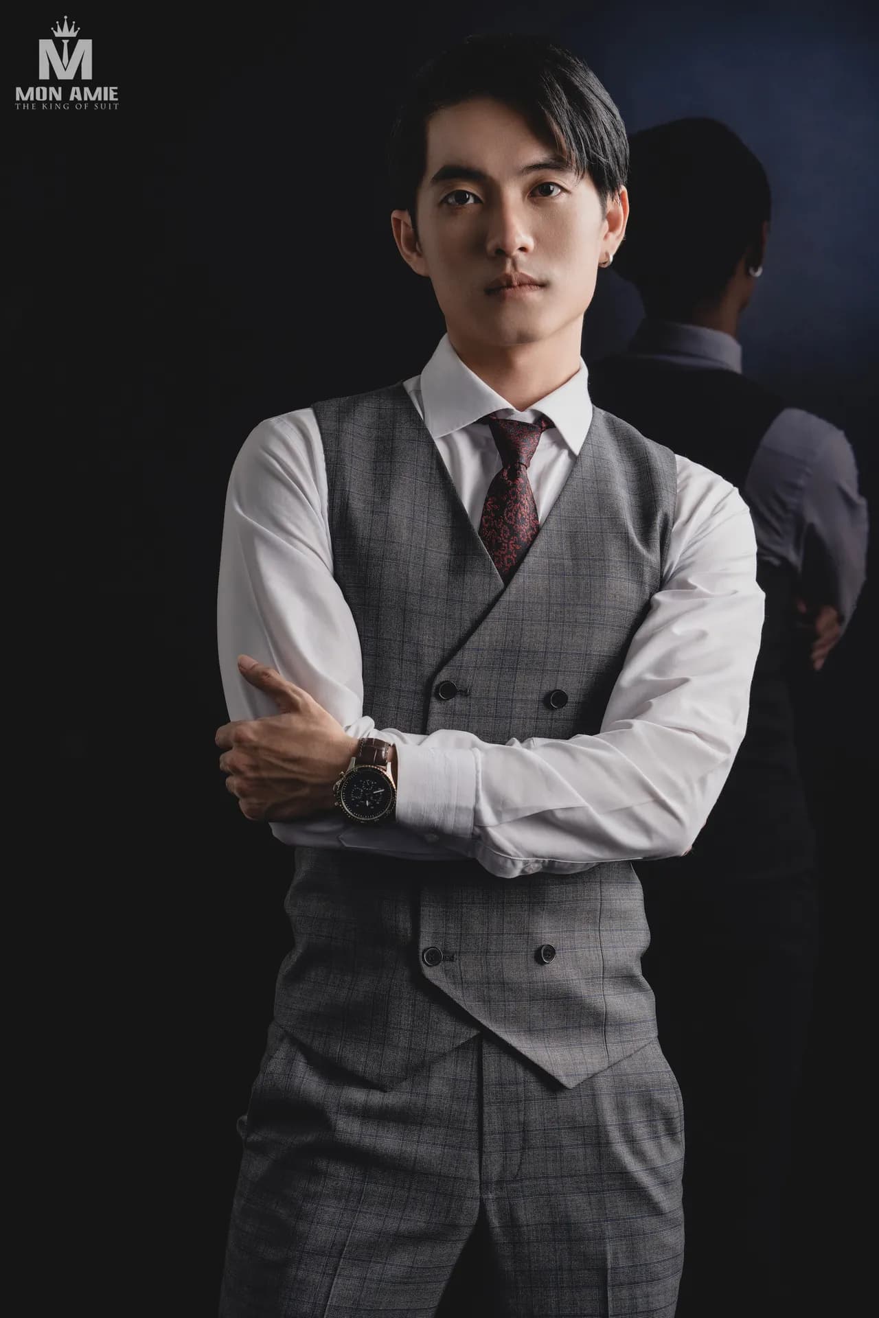 Gile xám, sơ mi trắng xắn tay, khoanh tay trên nền studio tối