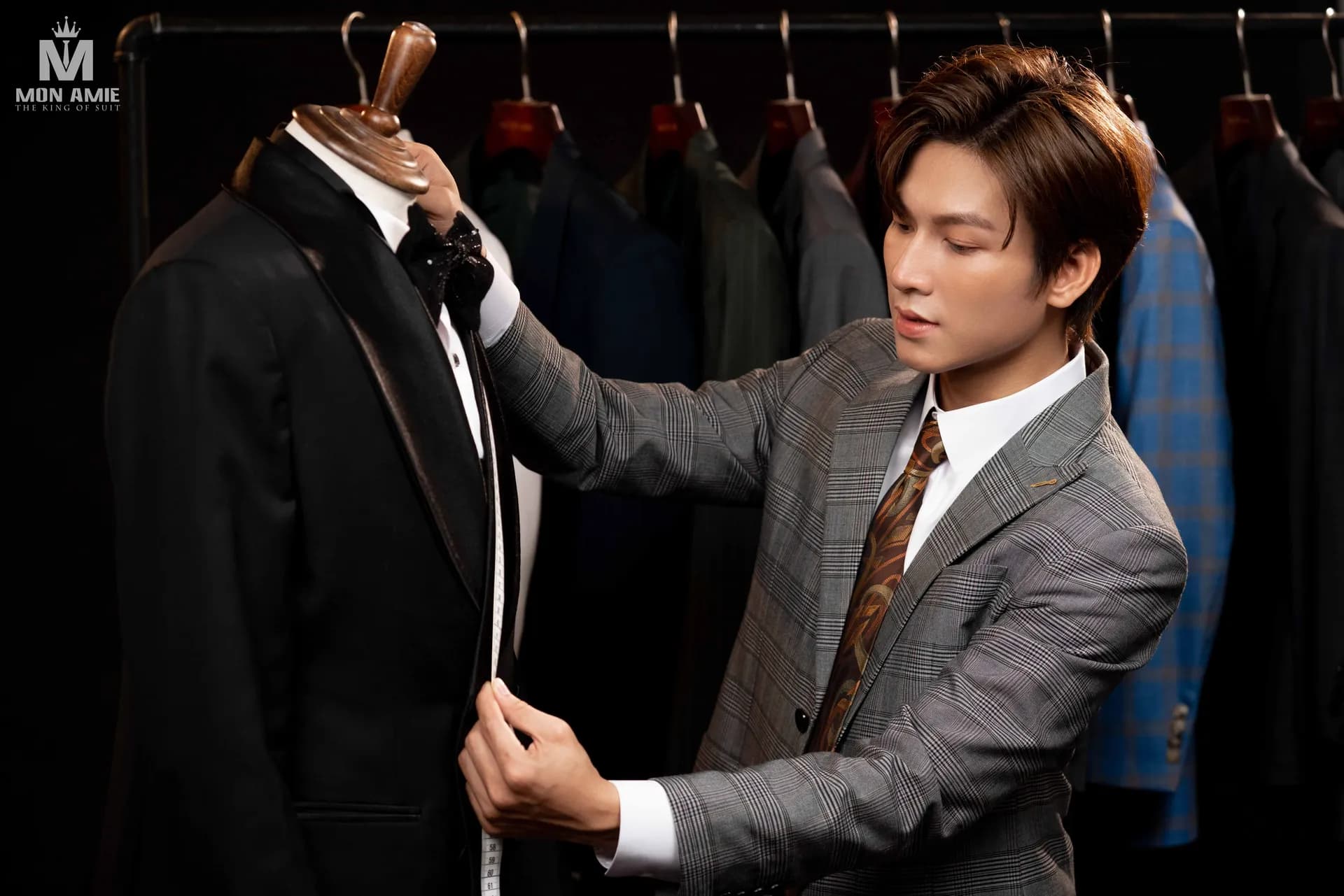 Người mẫu vest caro xám đo thước dây trên áo tuxedo đen cổ lụa