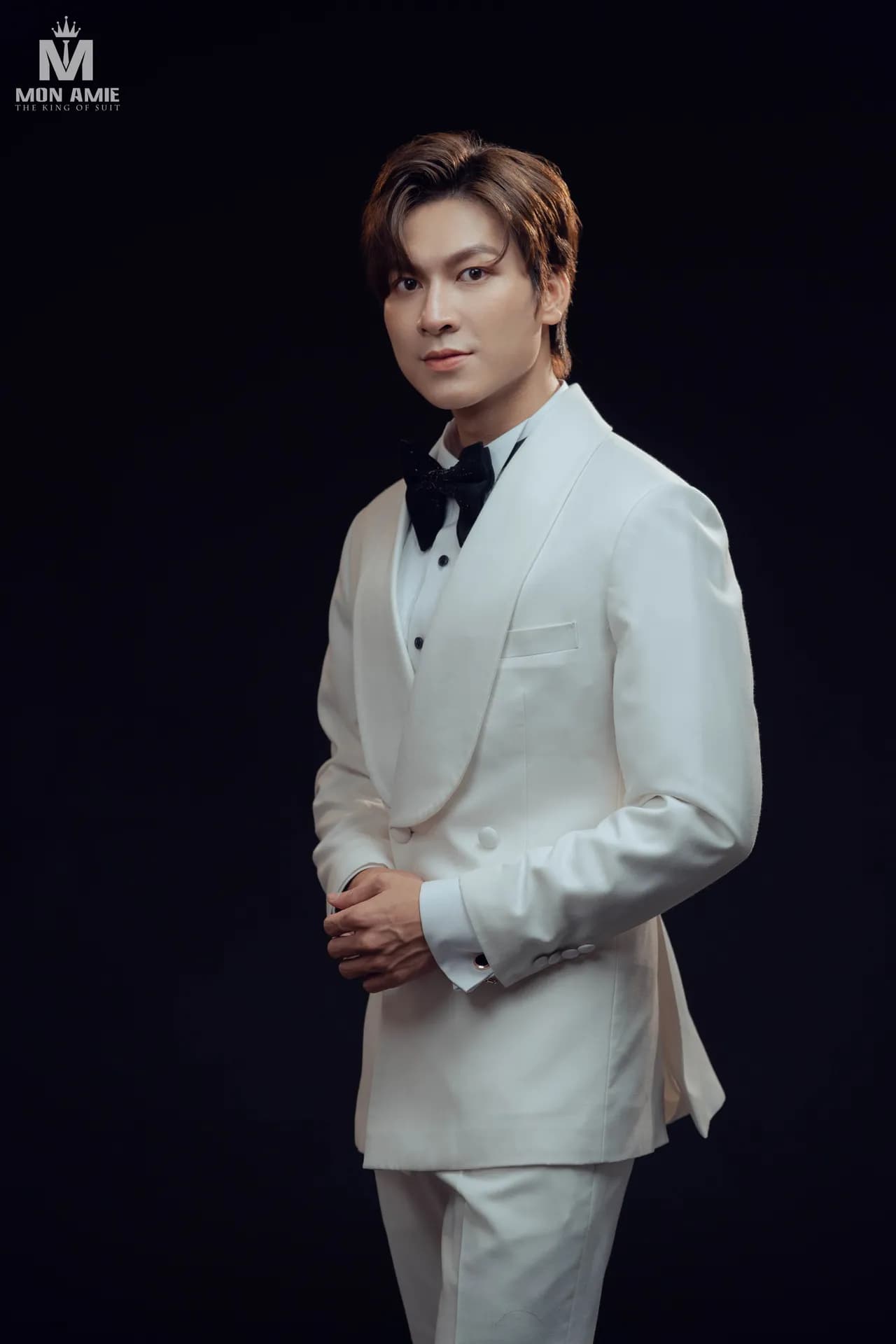 Tuxedo trắng cổ lụa hai hàng khuy, nơ nhung đen, nền studio tối