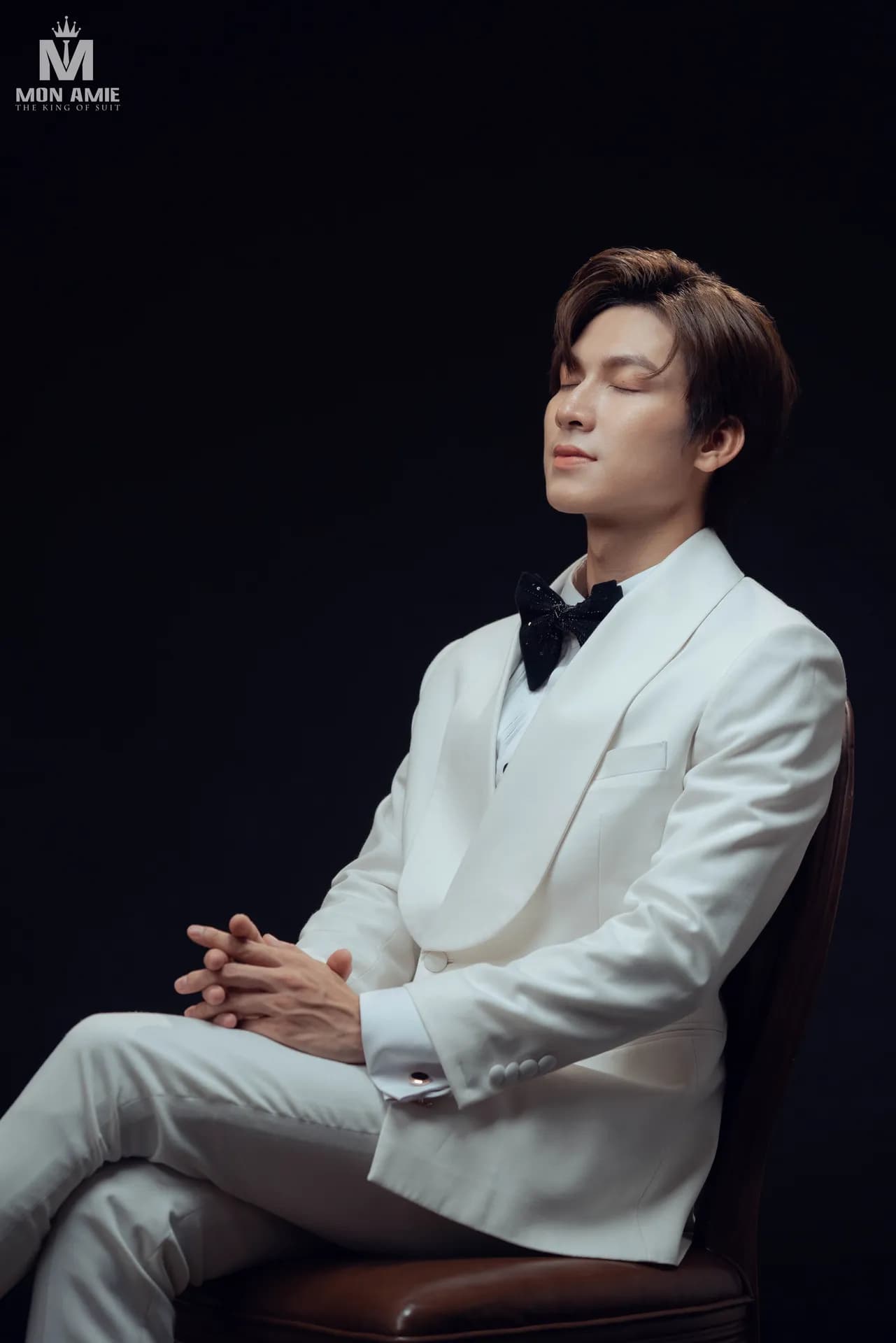 Tuxedo trắng cổ lụa, nơ đen, ngồi ghế da nâu