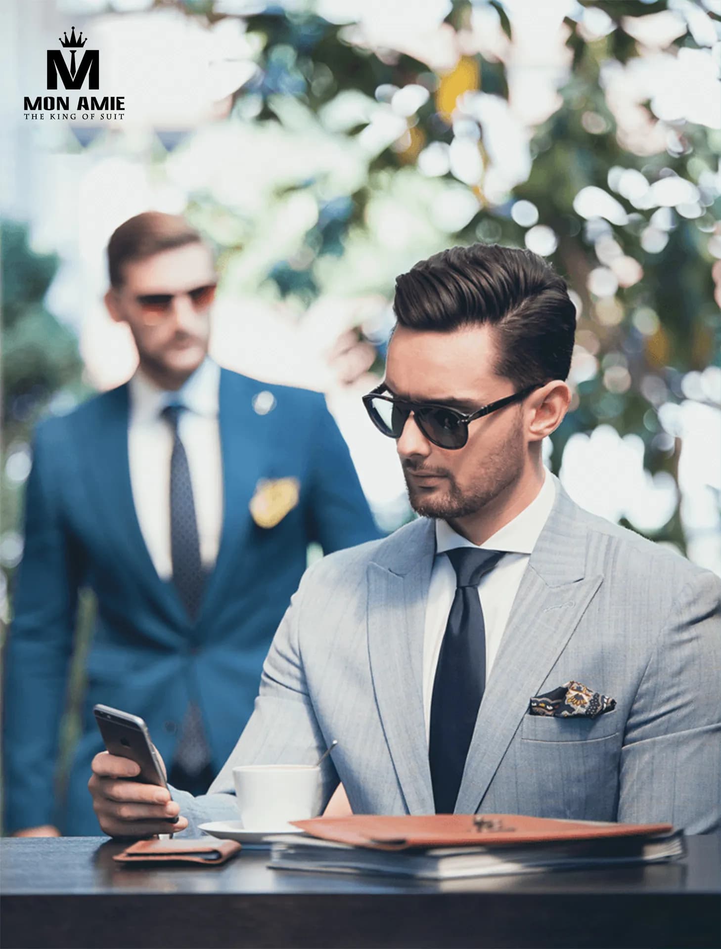 Hai quý ông suit xanh và xám nhạt, kính râm, làm việc bên bàn cà phê