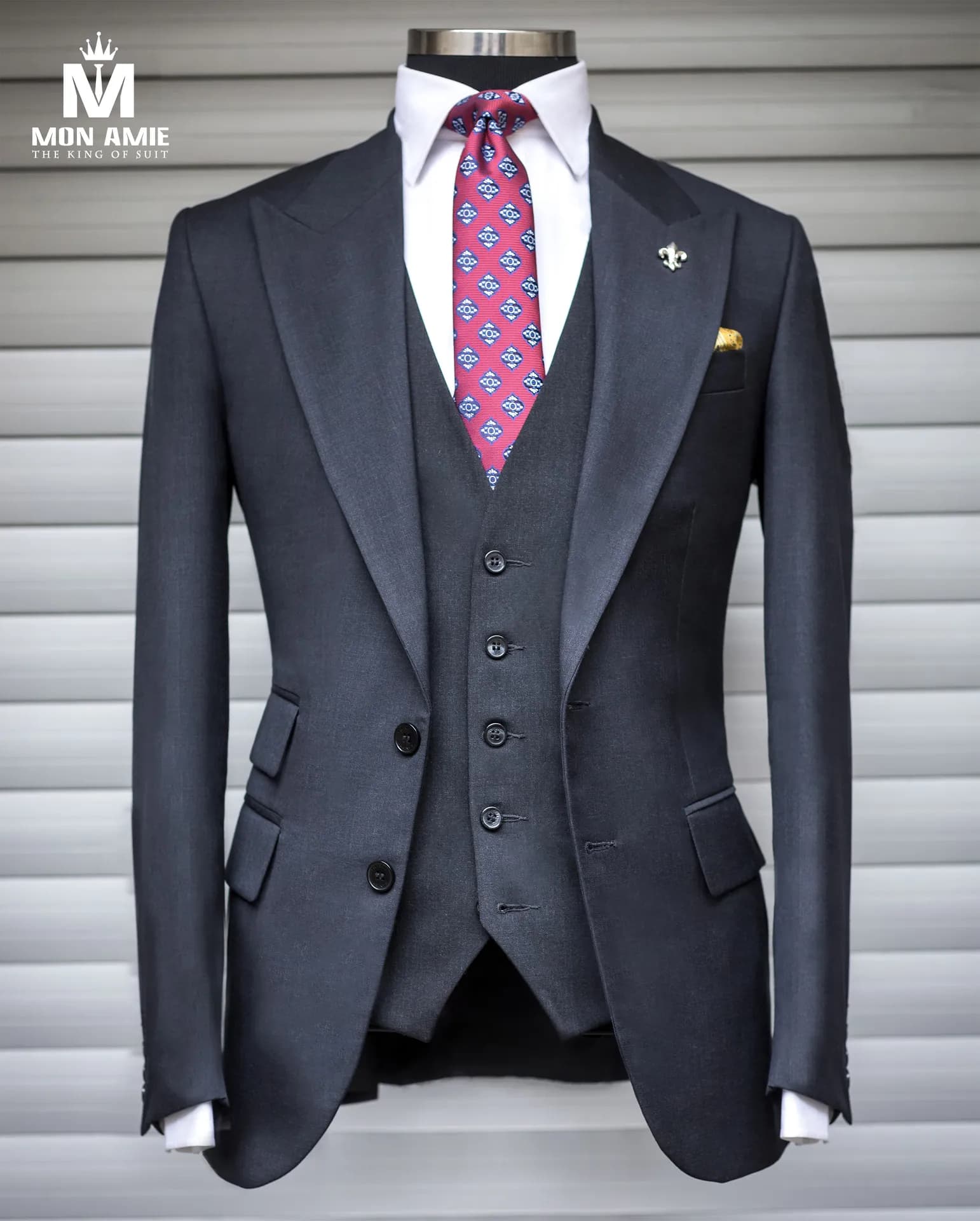 Suit ba mảnh xám than trên ma-nơ-canh, cà vạt họa tiết, ghim cài ve áo