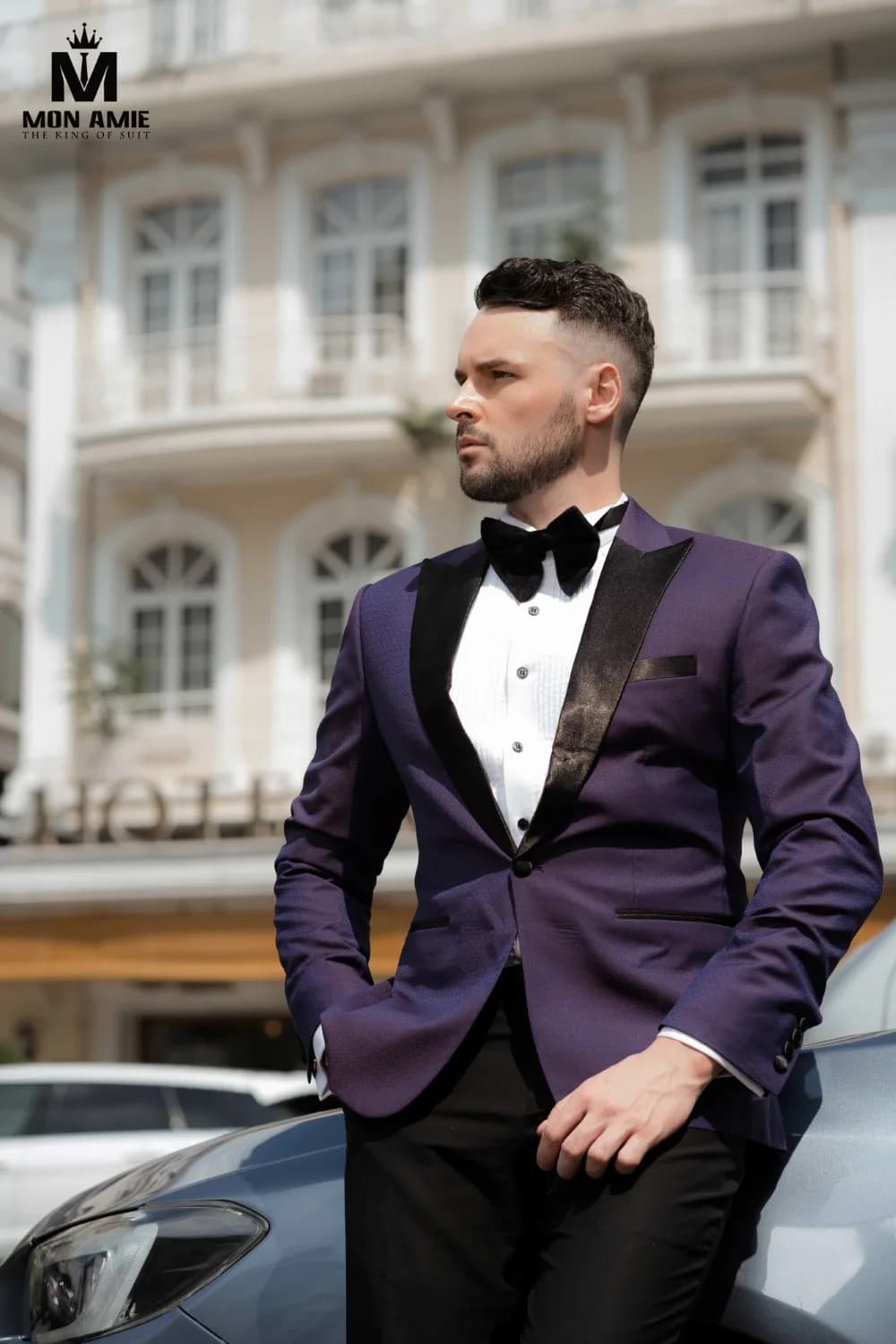 Tuxedo tím cận cảnh, ve satin đen và nơ bên xe hơi trước khách sạn cổ