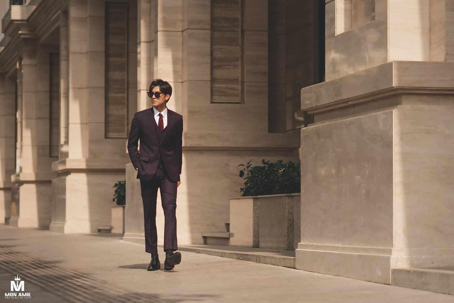 Suit nâu cà phê, ngồi ghế gỗ đan chéo giữa phòng tường phào chỉ