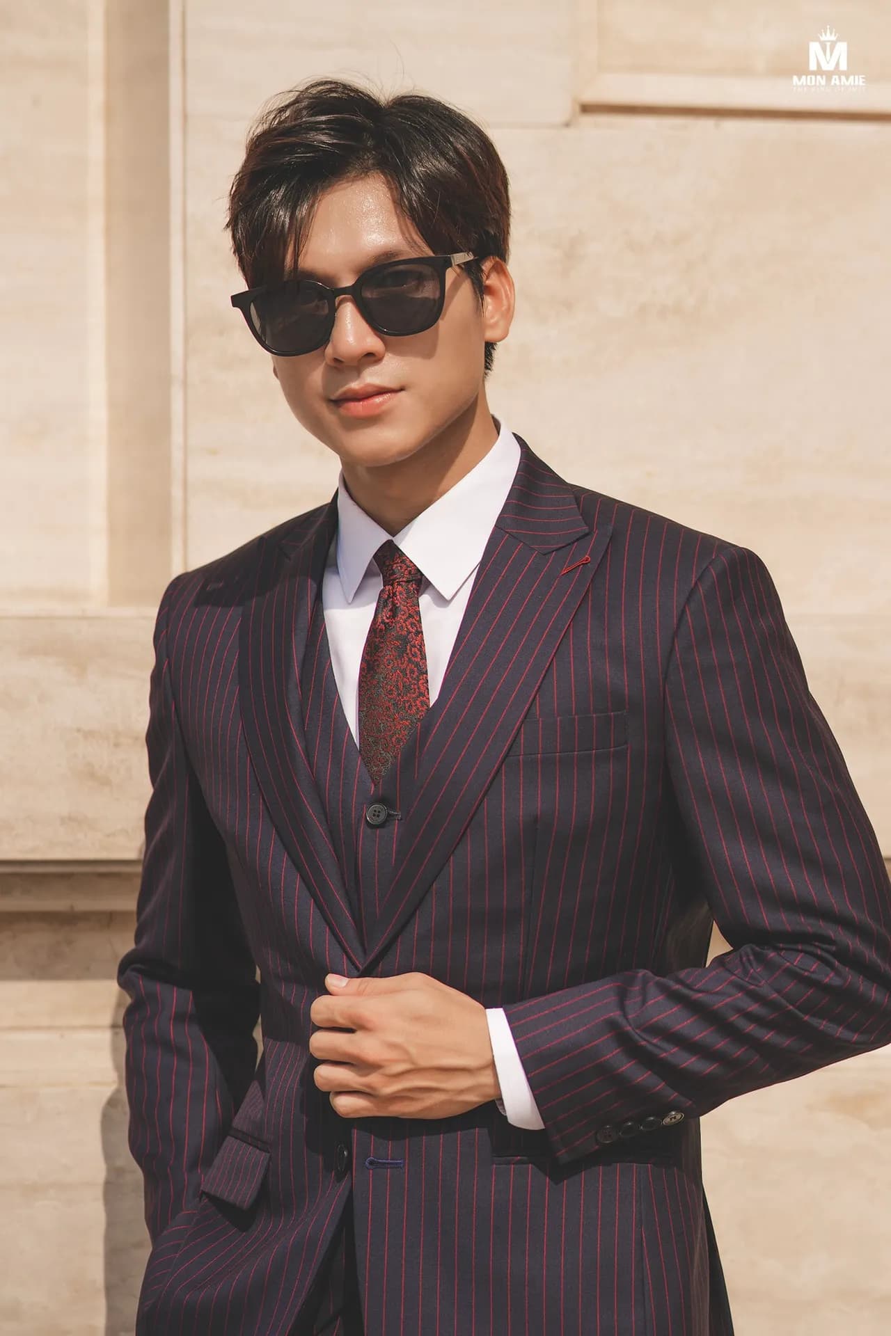 Suit ba mảnh kẻ sọc đỏ đô, cà vạt họa tiết, kính râm, tay cài khuy