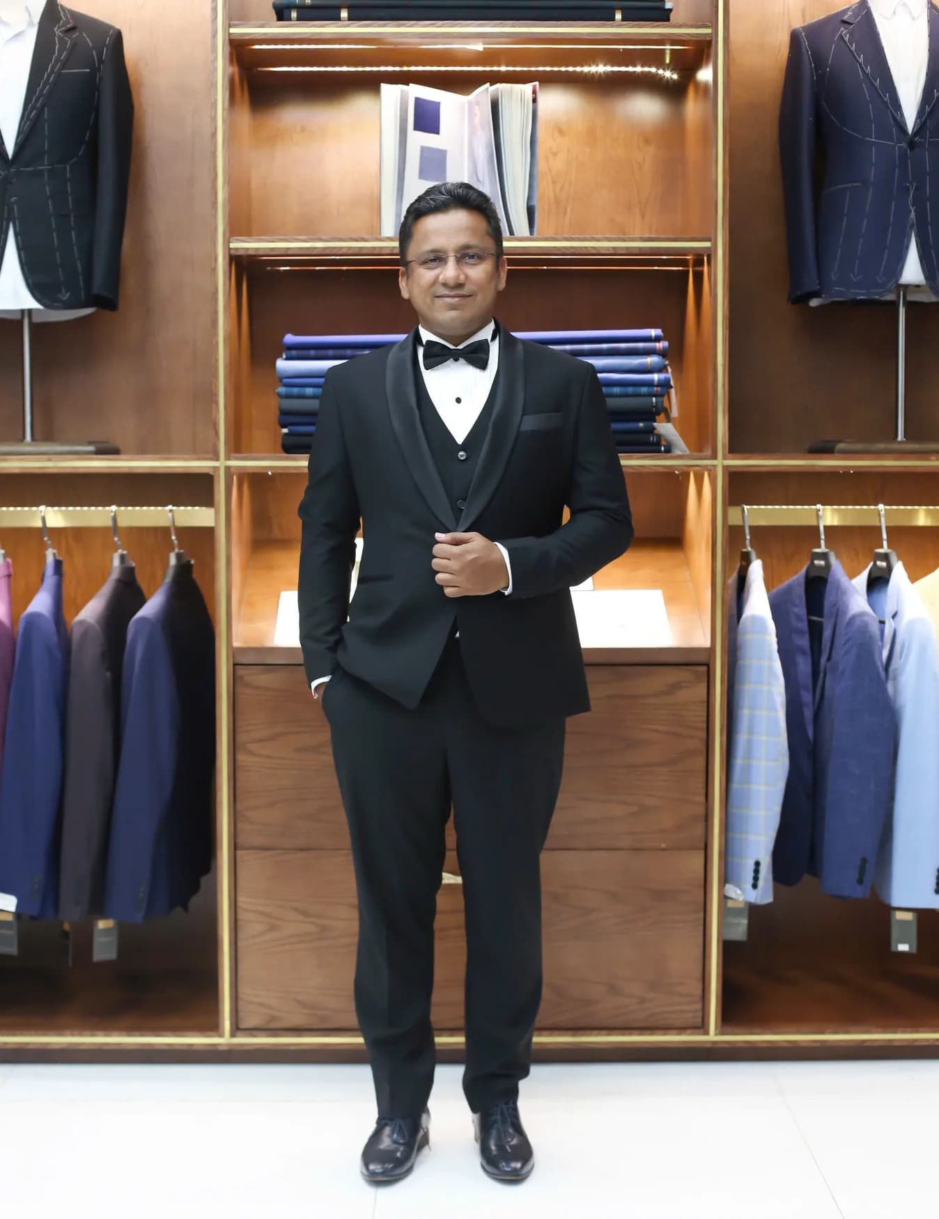 Quý ông tuxedo đen ba mảnh, nơ đen, showroom gỗ sang