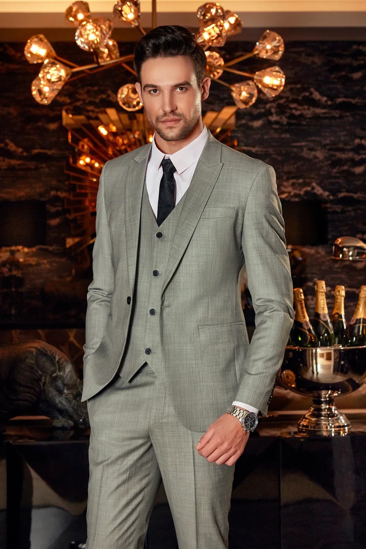 Suit ba mảnh xám ghi vân dệt, cà vạt đen hoạ tiết, ánh vàng sang trọng phía sau