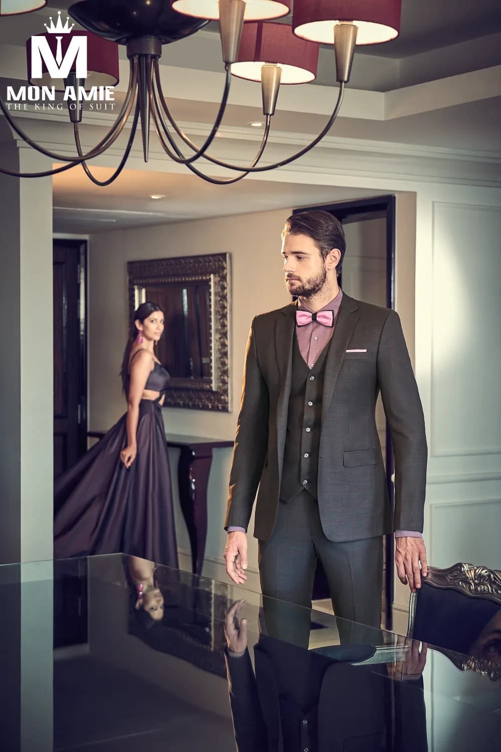 Suit ba mảnh xám khói, sơ mi tím nhạt và nơ hồng, bên bóng váy dạ hội xa xa