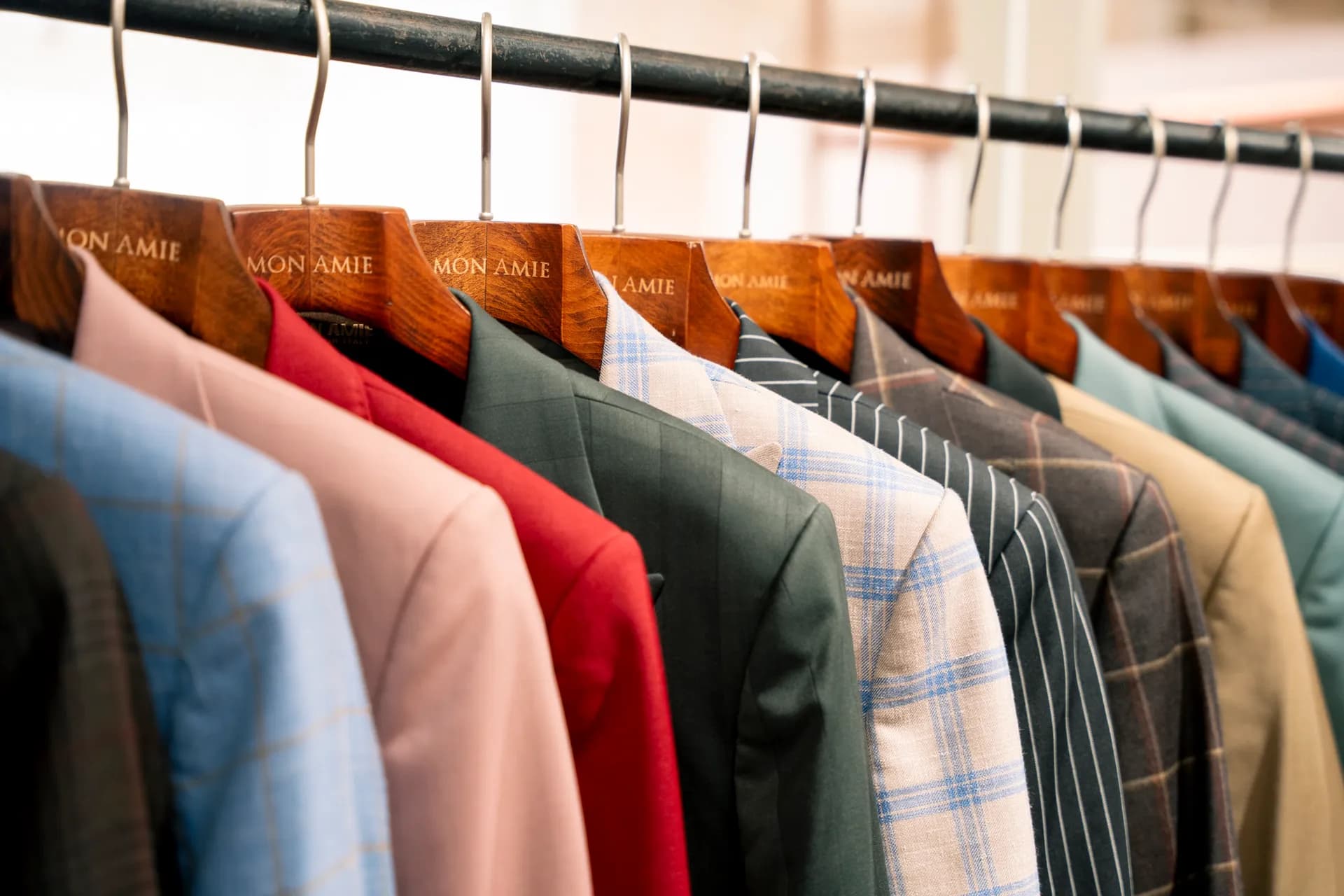 Hàng áo vest nhiều gam màu trên giá, móc gỗ khắc Mon Amie