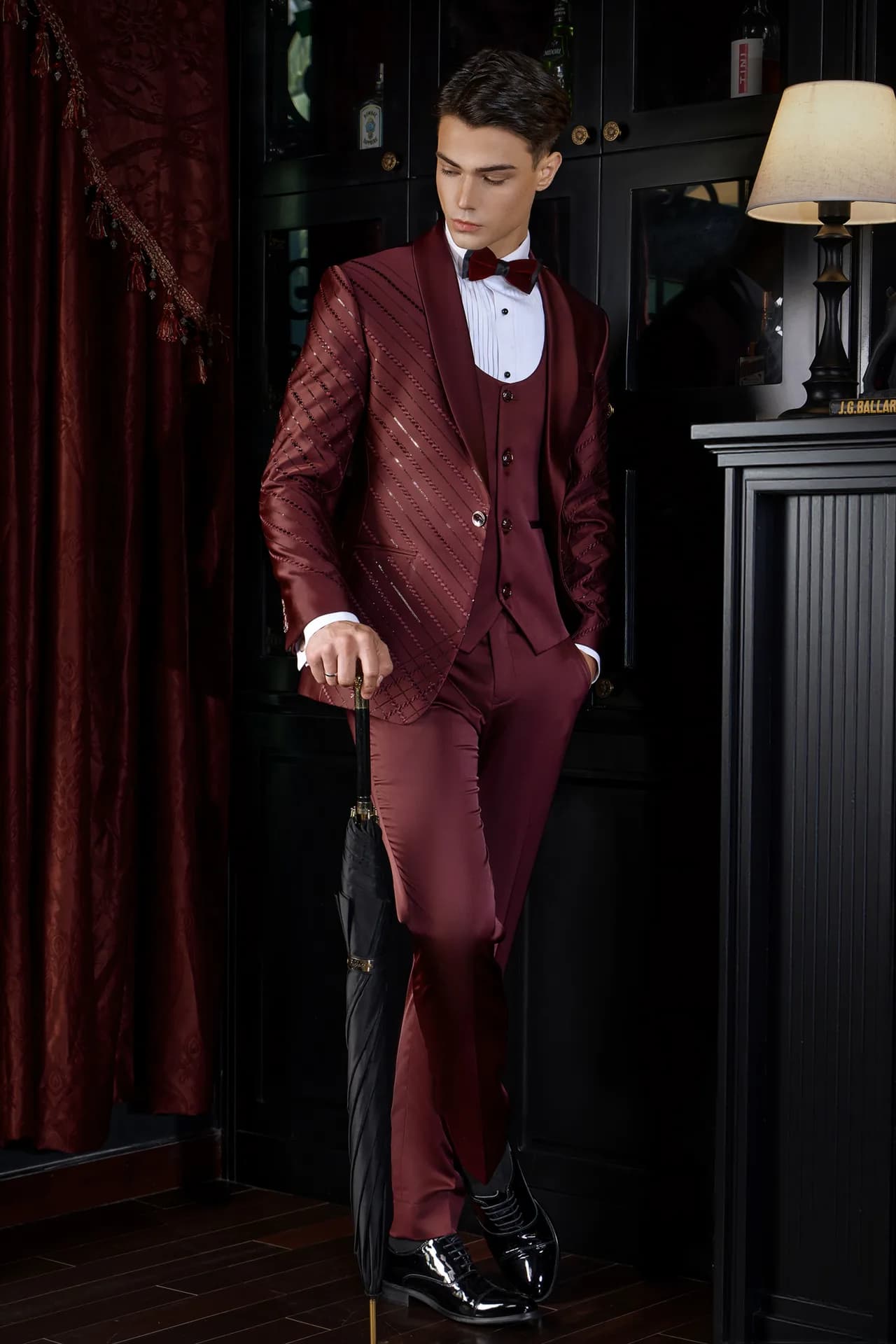 Suit đỏ rượu vang kim tuyến chéo ba mảnh, nơ đỏ, ô đen làm điểm nhấn.