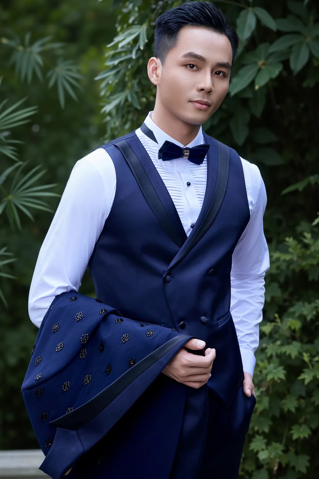 Suit navy ve shawl ngồi bên hồ bơi, nơ đen, giày da bóng.
