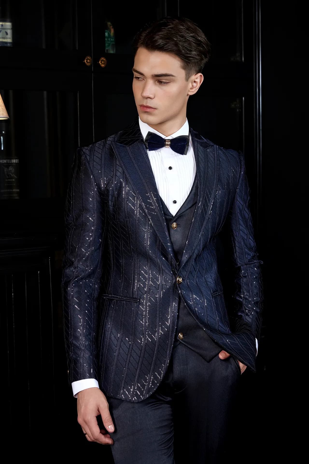 Tuxedo họa tiết ánh kim xanh navy, nơ đen, cận cảnh phòng thư viện tối