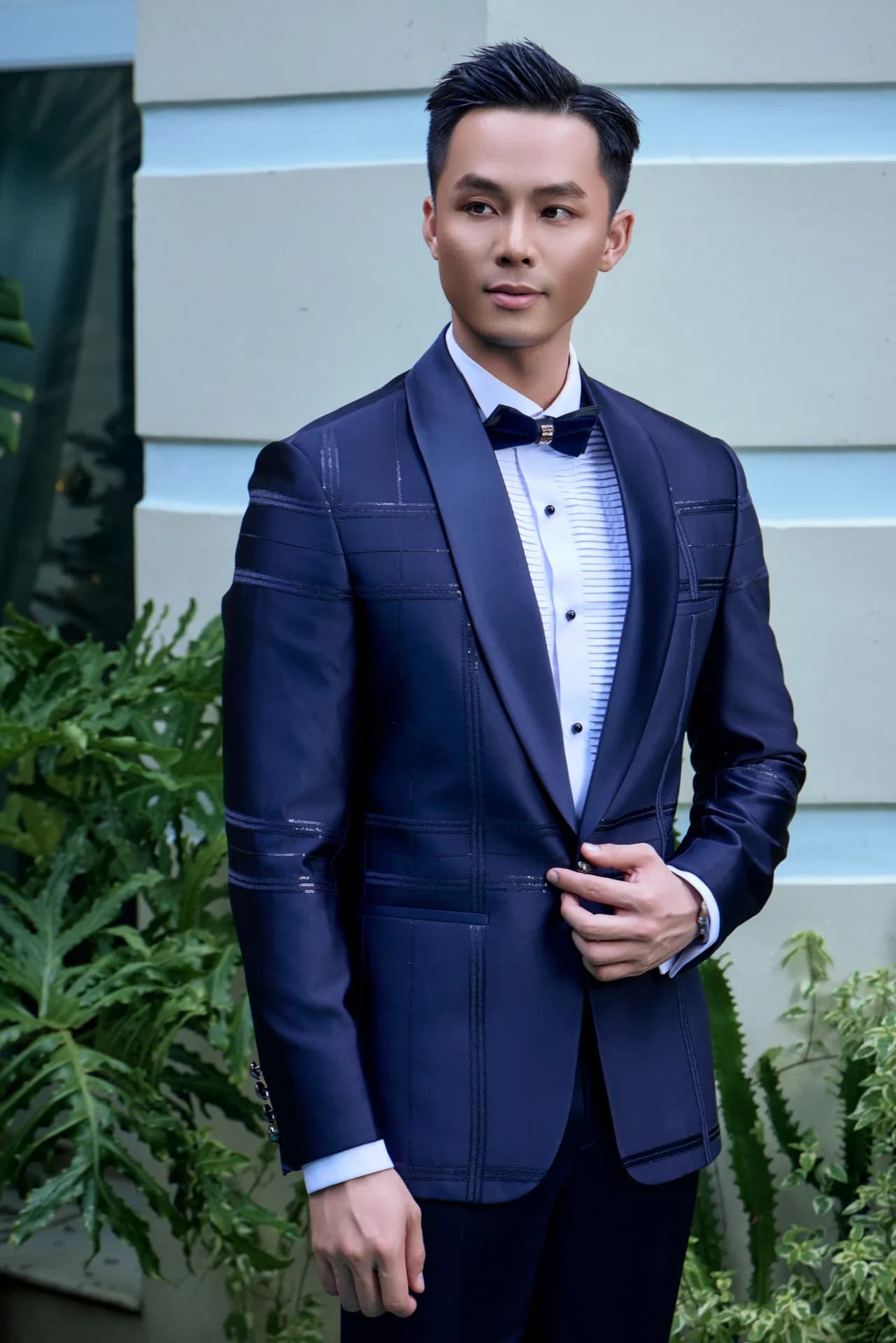 Suit xanh navy nơ đen, chỉnh khuy áo, cận cảnh bên hồ bơi