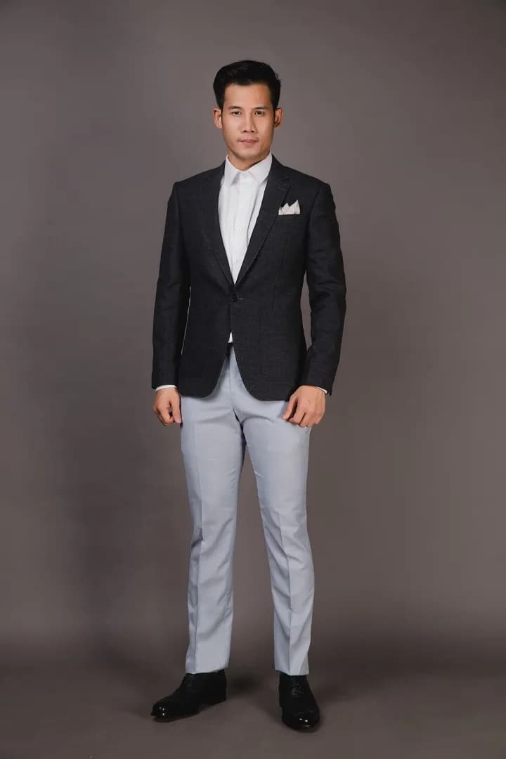 Suit navy kẻ mảnh ba mảnh, dáng ngồi sofa bọc họa tiết, giày da nâu