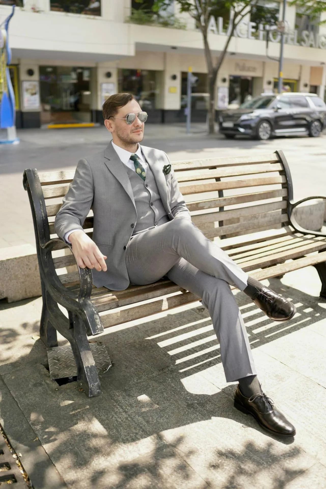 Suit ba mảnh xám nhạt, khách ngồi ghế băng phố, kính râm