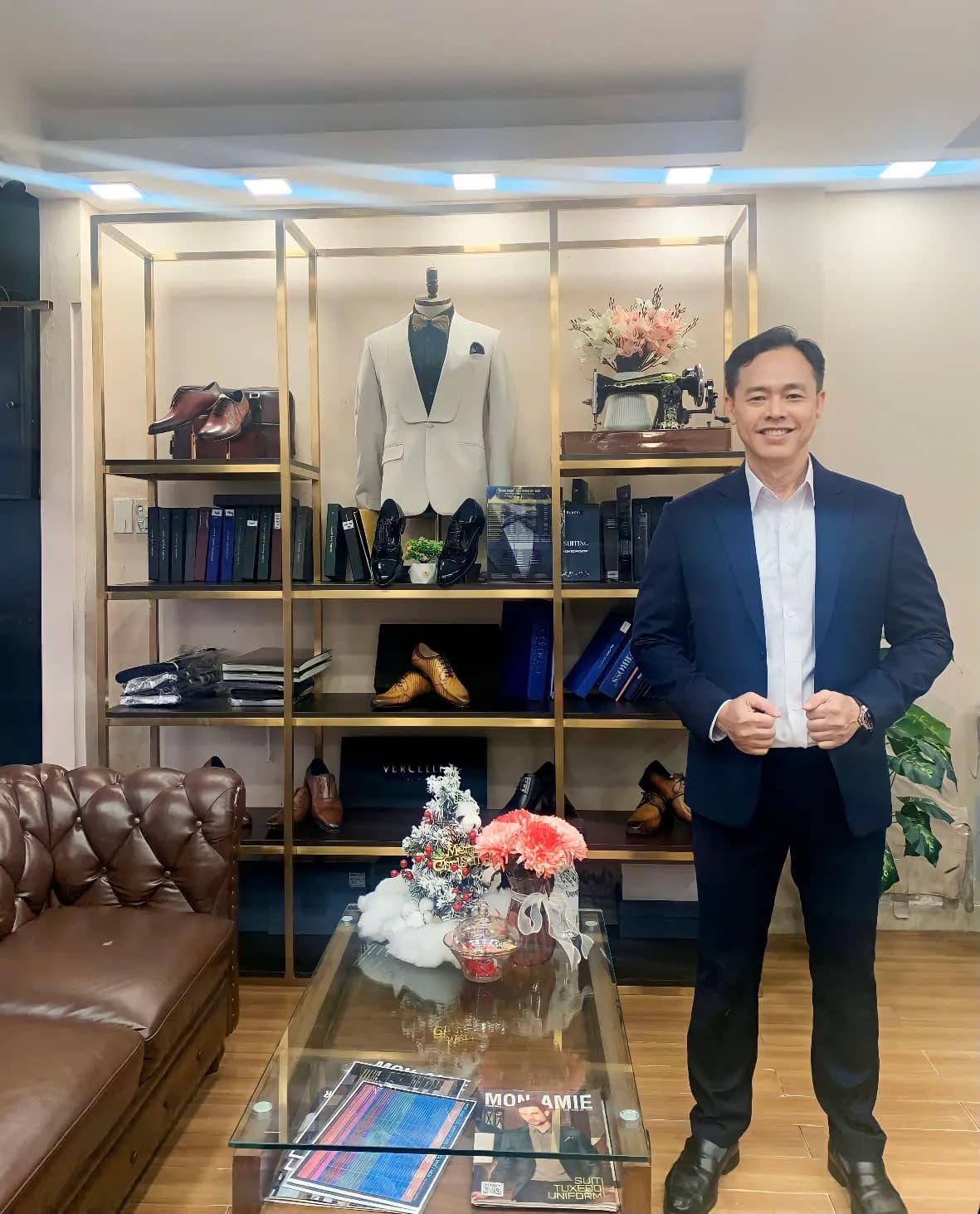 Khách mặc blazer navy sơ mi trắng mở cổ, cười tự tin tại showroom