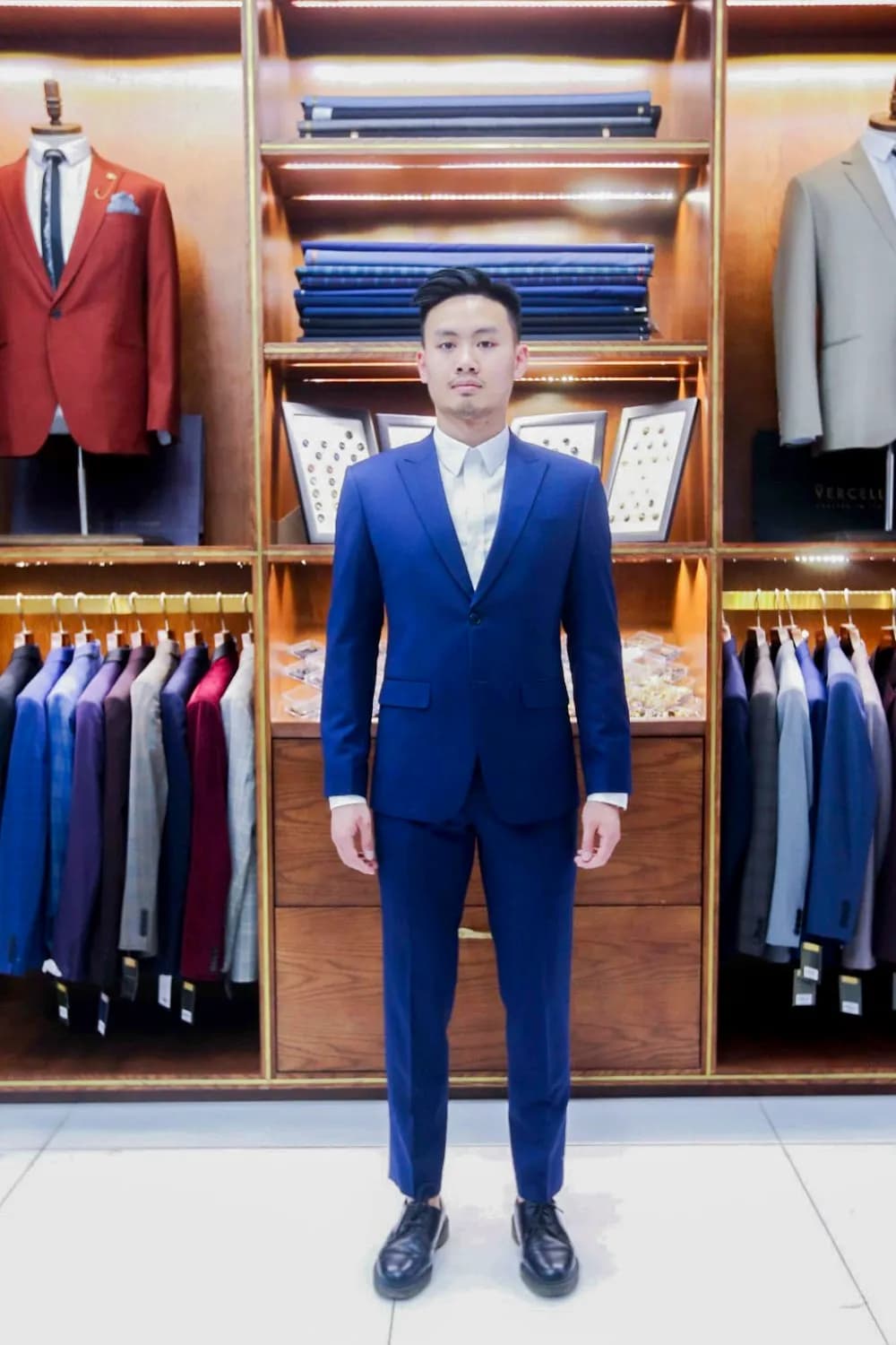 Khách mặc suit xanh dương rực rỡ trước tủ vải gỗ