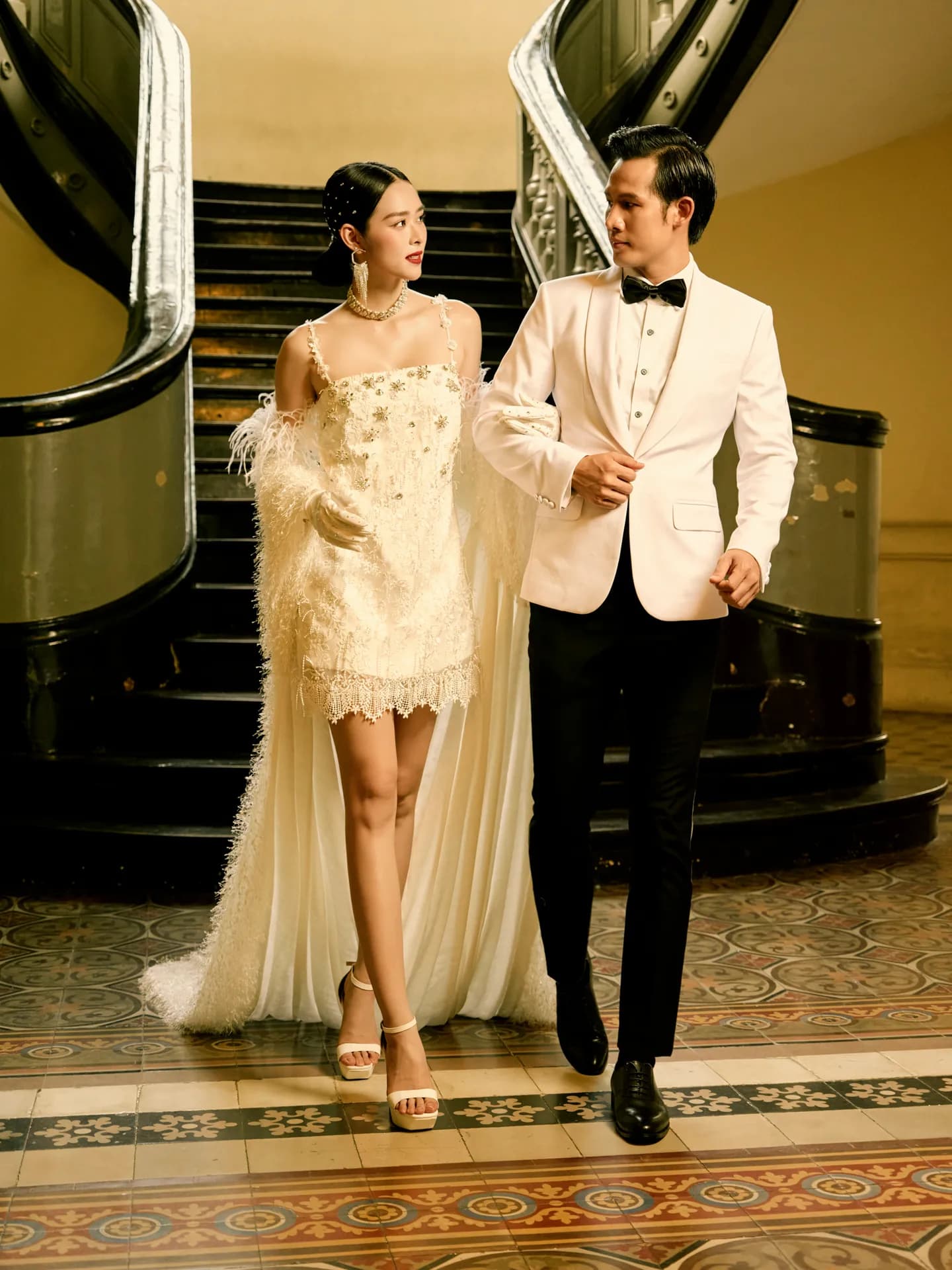 Tuxedo trắng nơ đen sánh bước cùng váy ngắn lông vũ bên cầu thang cổ