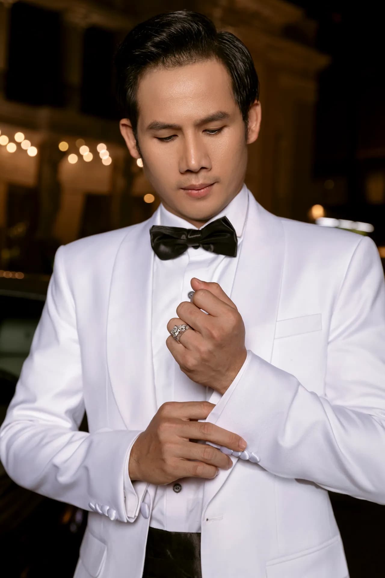 Tuxedo trắng thắt nơ đen, chỉnh khuy măng sét, cận cảnh