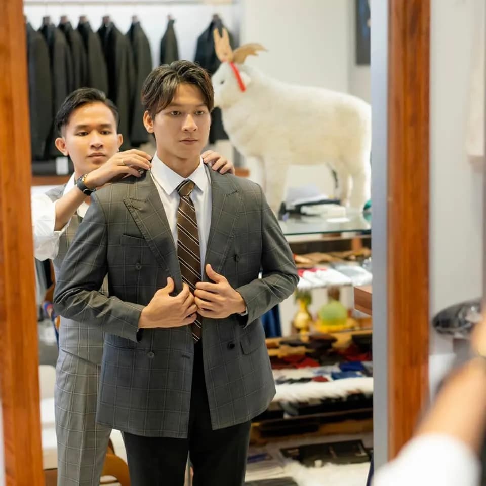 Thử vest xám ca-rô hai hàng, thợ may chỉnh vai áo cho khách