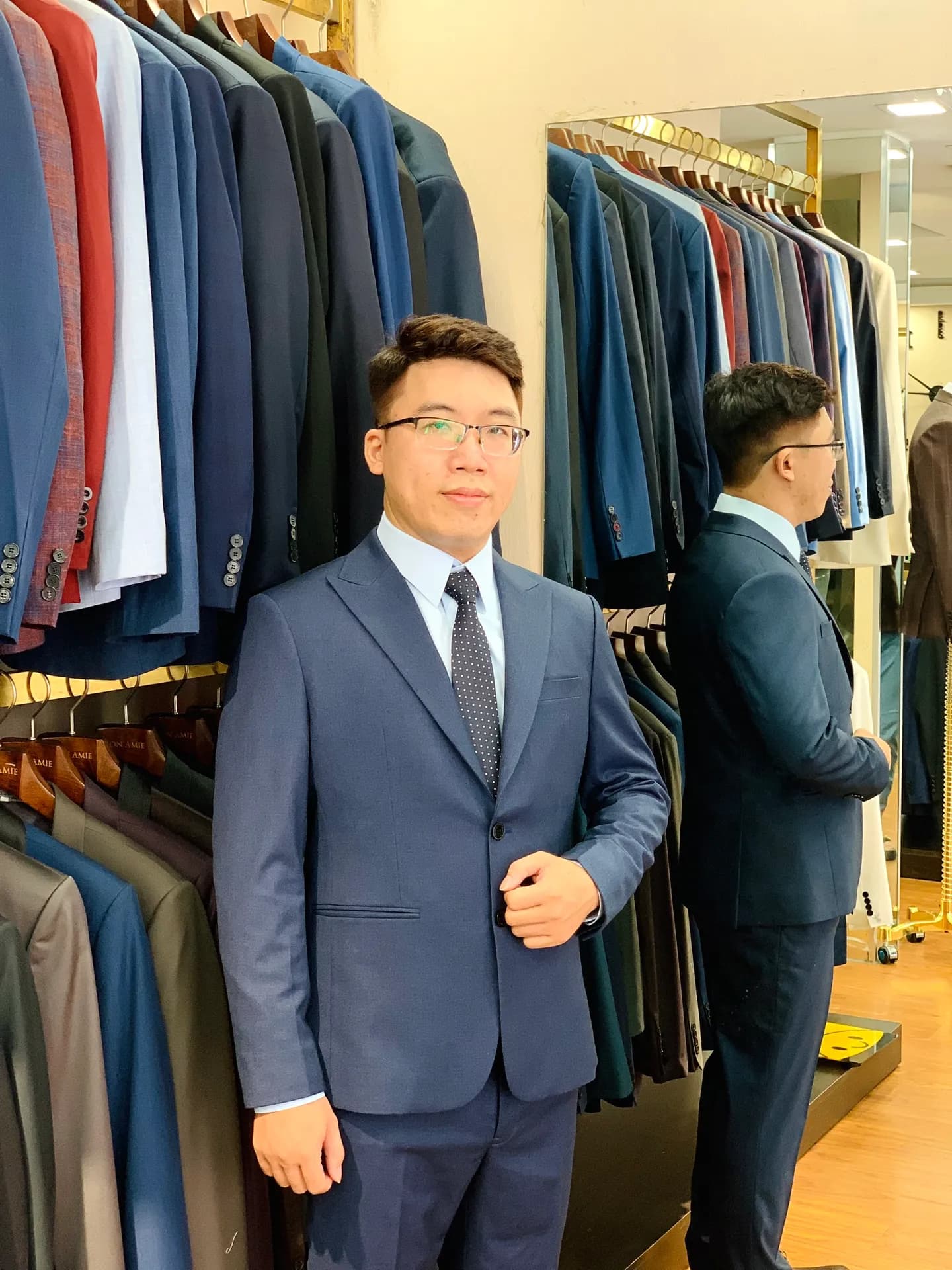 Suit xanh navy cà vạt chấm bi, chỉnh khuy áo giữa dãy vest treo