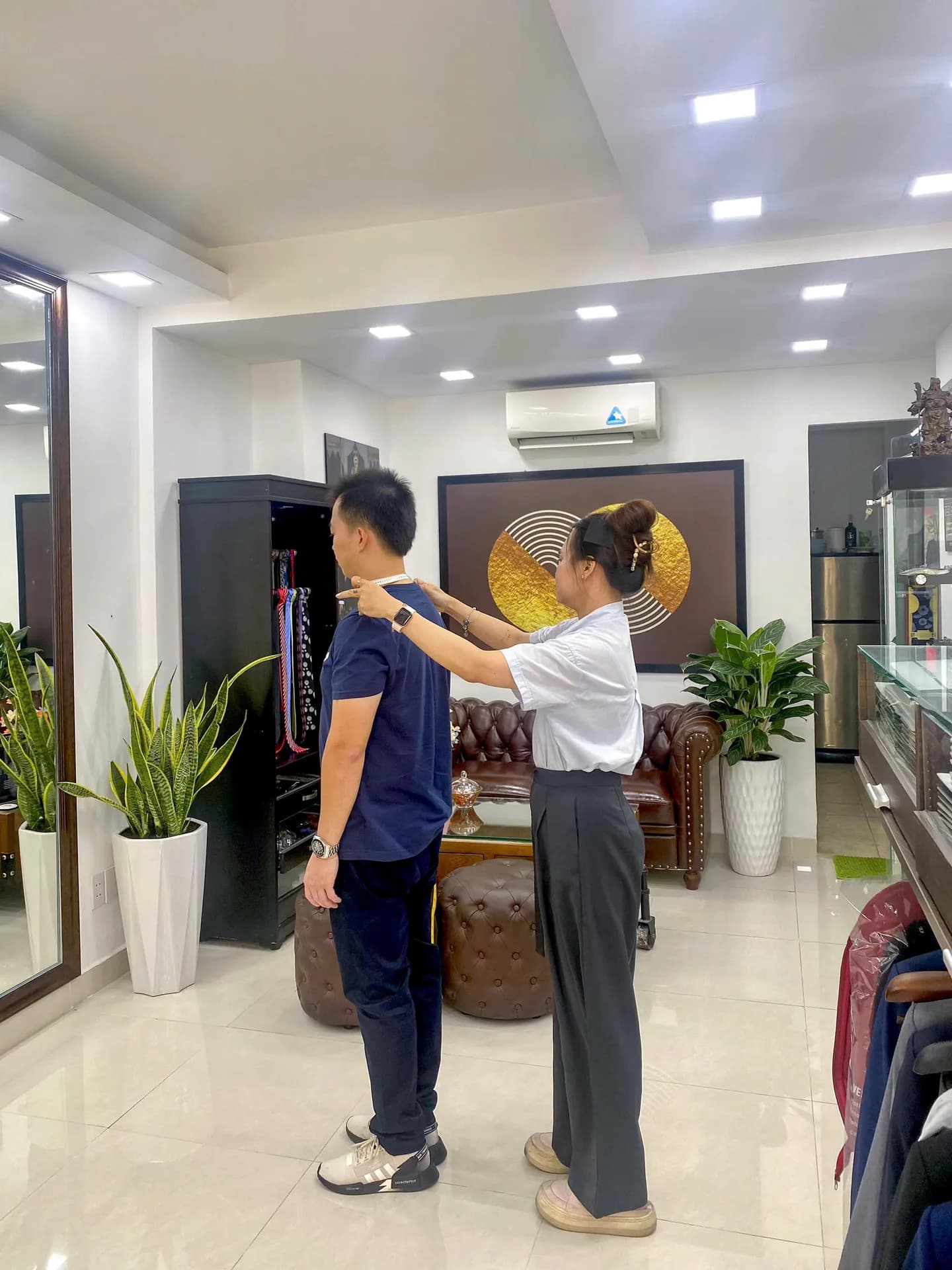 Nhân viên đo vai cho khách trong showroom, khoảnh khắc đo may