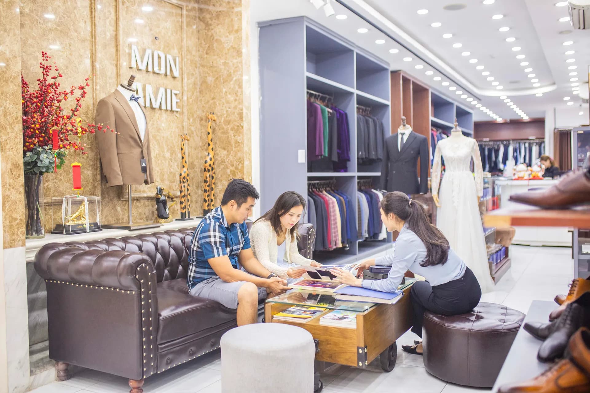 Khách ngồi sofa Chesterfield cùng nhân viên chọn vải, tư vấn