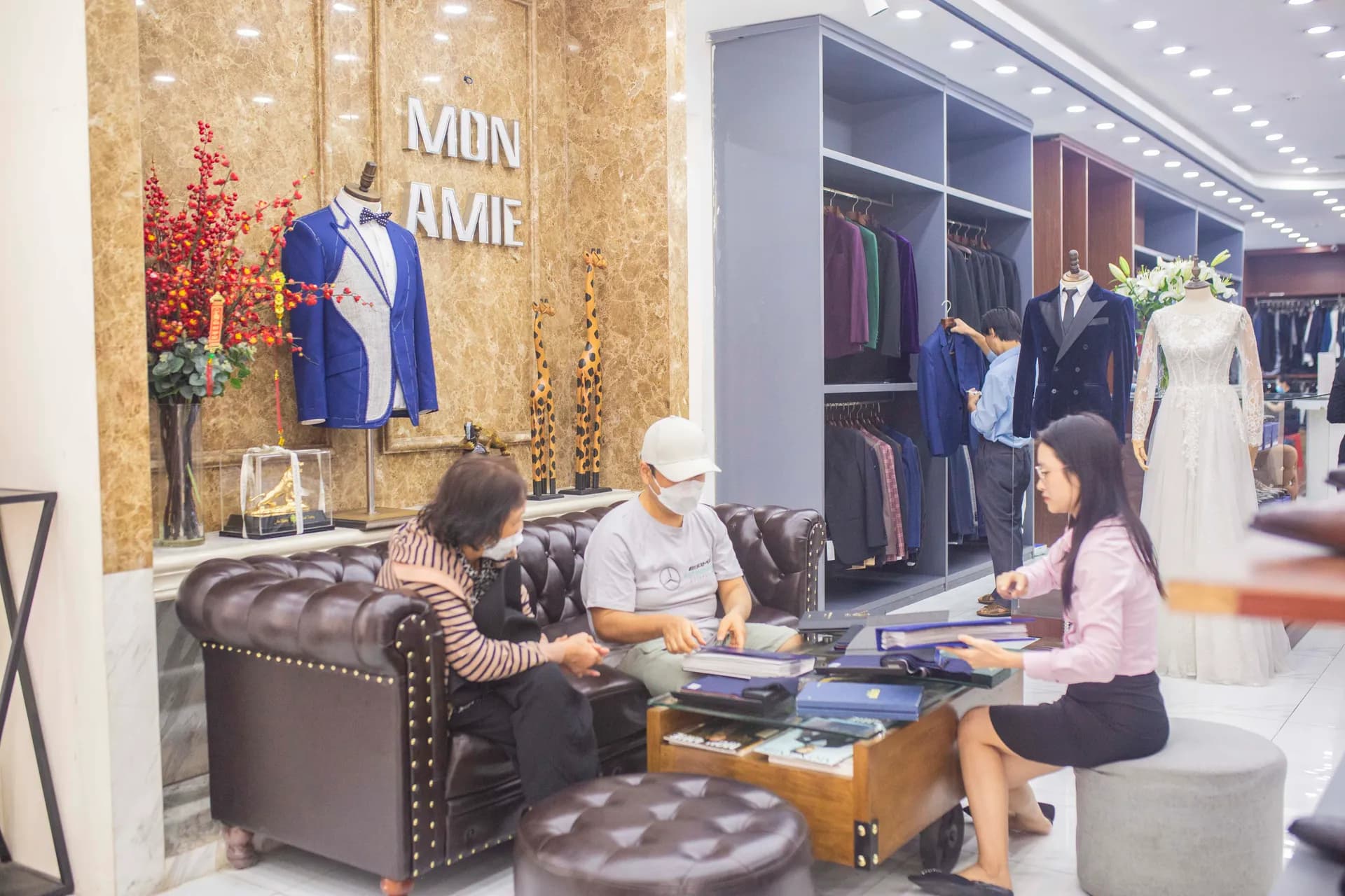Nhân viên tư vấn chọn vải cho khách trên sofa da tại showroom